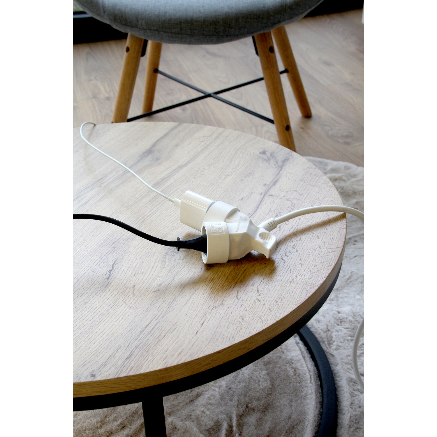 Multiprise blanche sur table en bois, câble noir branché.