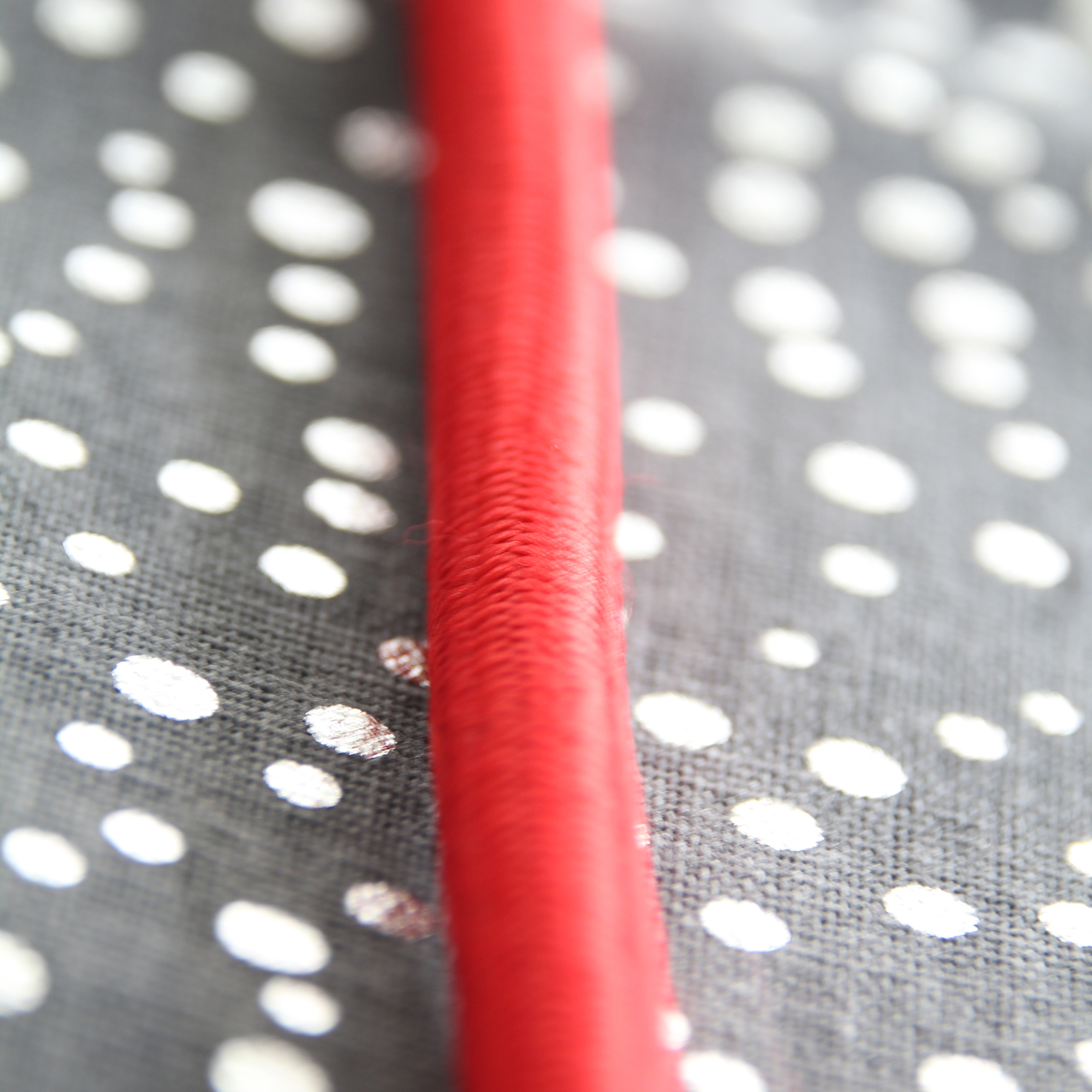 Câble rouge sur un tissu gris et blanc à pois.