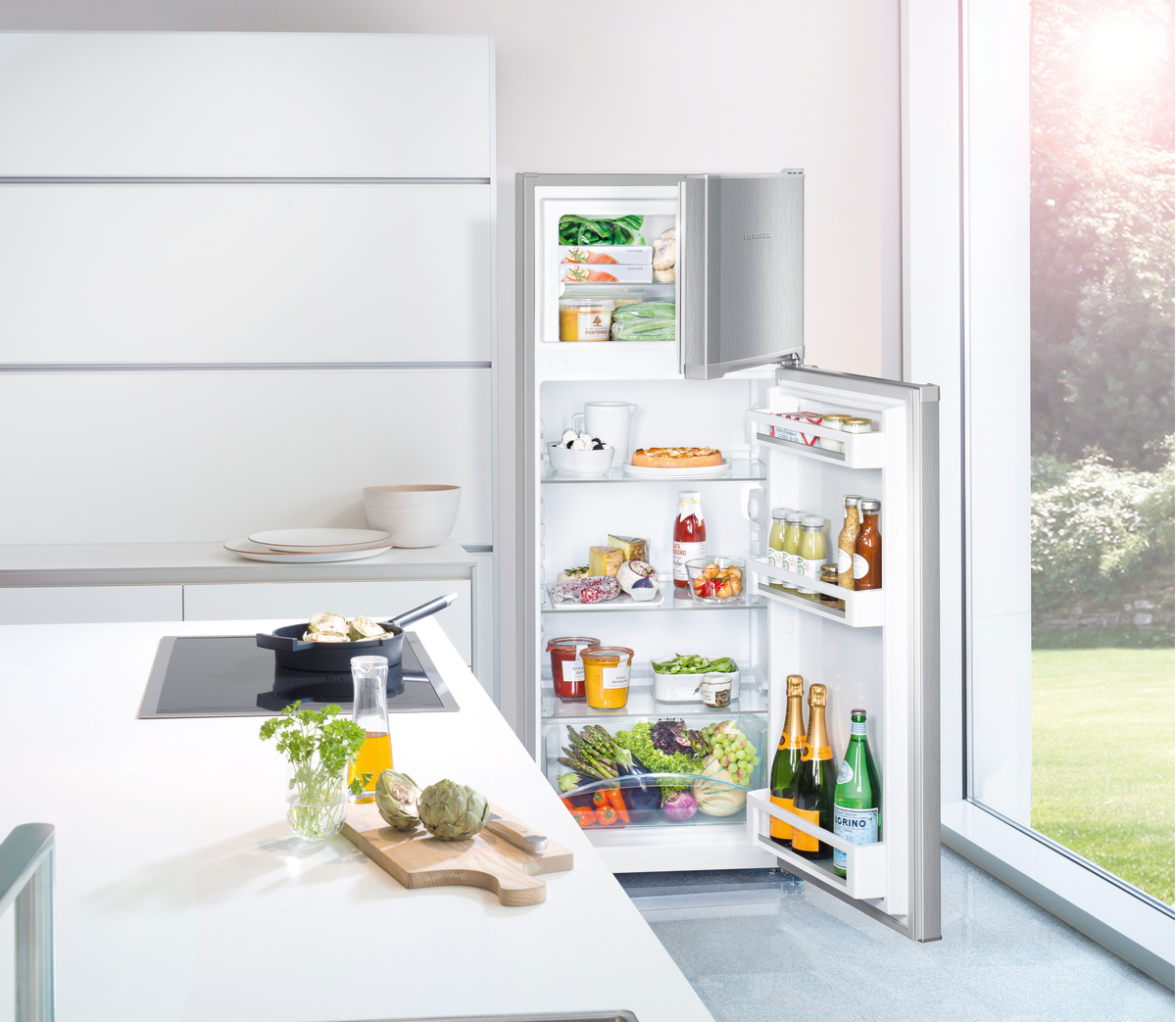 Offener Kühlschrank mit Lebensmitteln in einer Küche mit weißer Arbeitsplatte.
