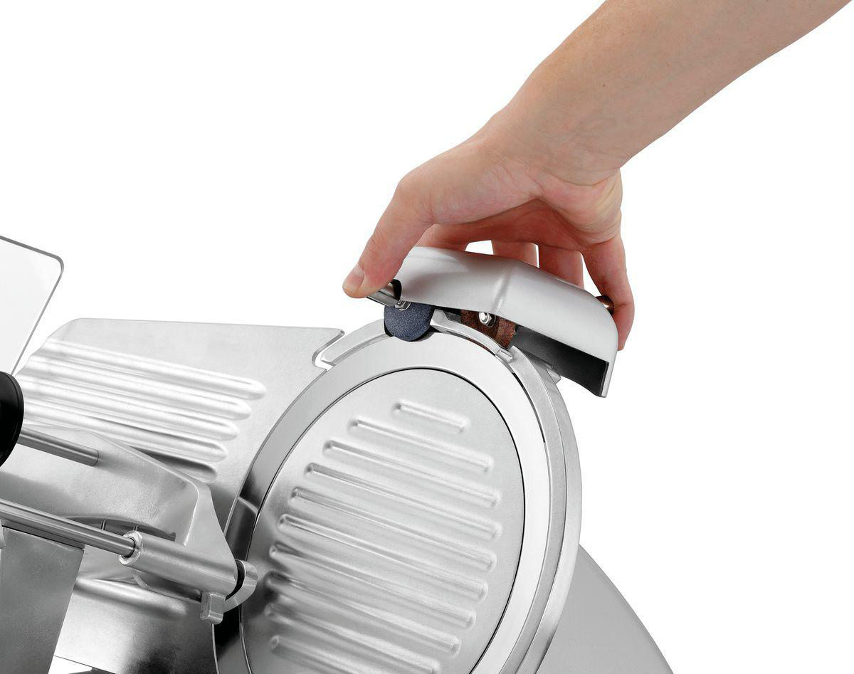 Eine Hand bedient einen silbernen Fleischschneider. Die Klinge ist sichtbar, und die Hand ist positioniert, um die Maschine einzustellen.