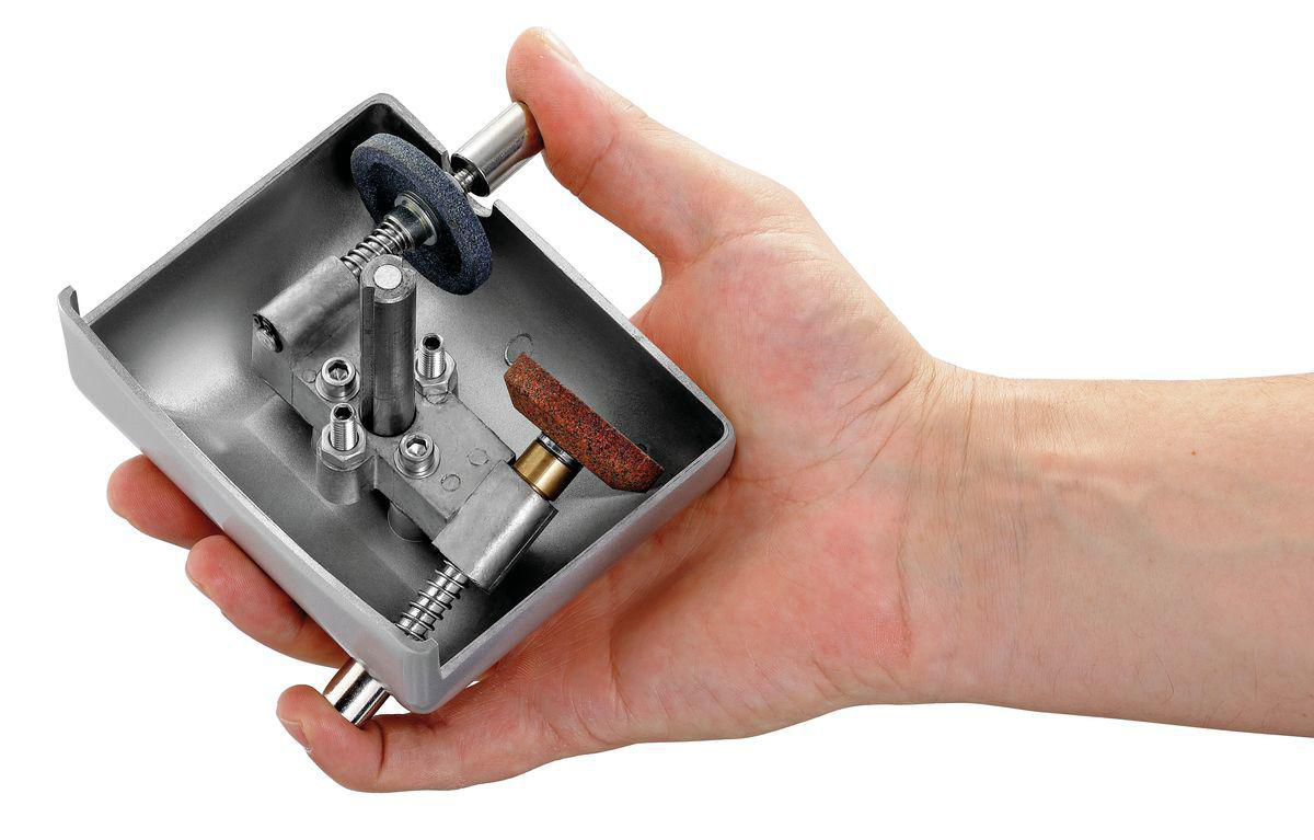 Eine Hand, die ein Metall-Schärfwerkzeug hält. Das Werkzeug ist geöffnet.