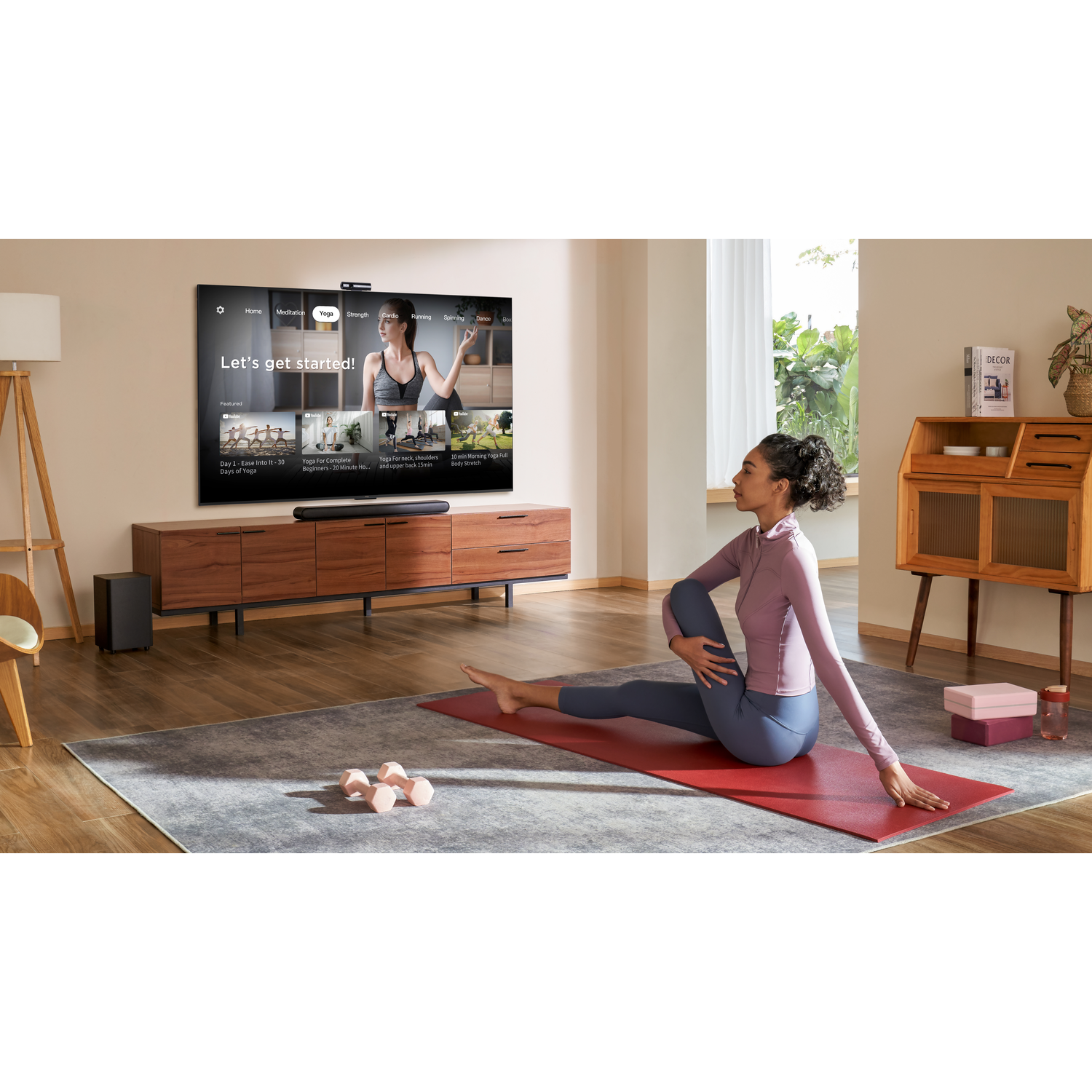 Een vrouw doet yoga voor een tv met een yogavideo.