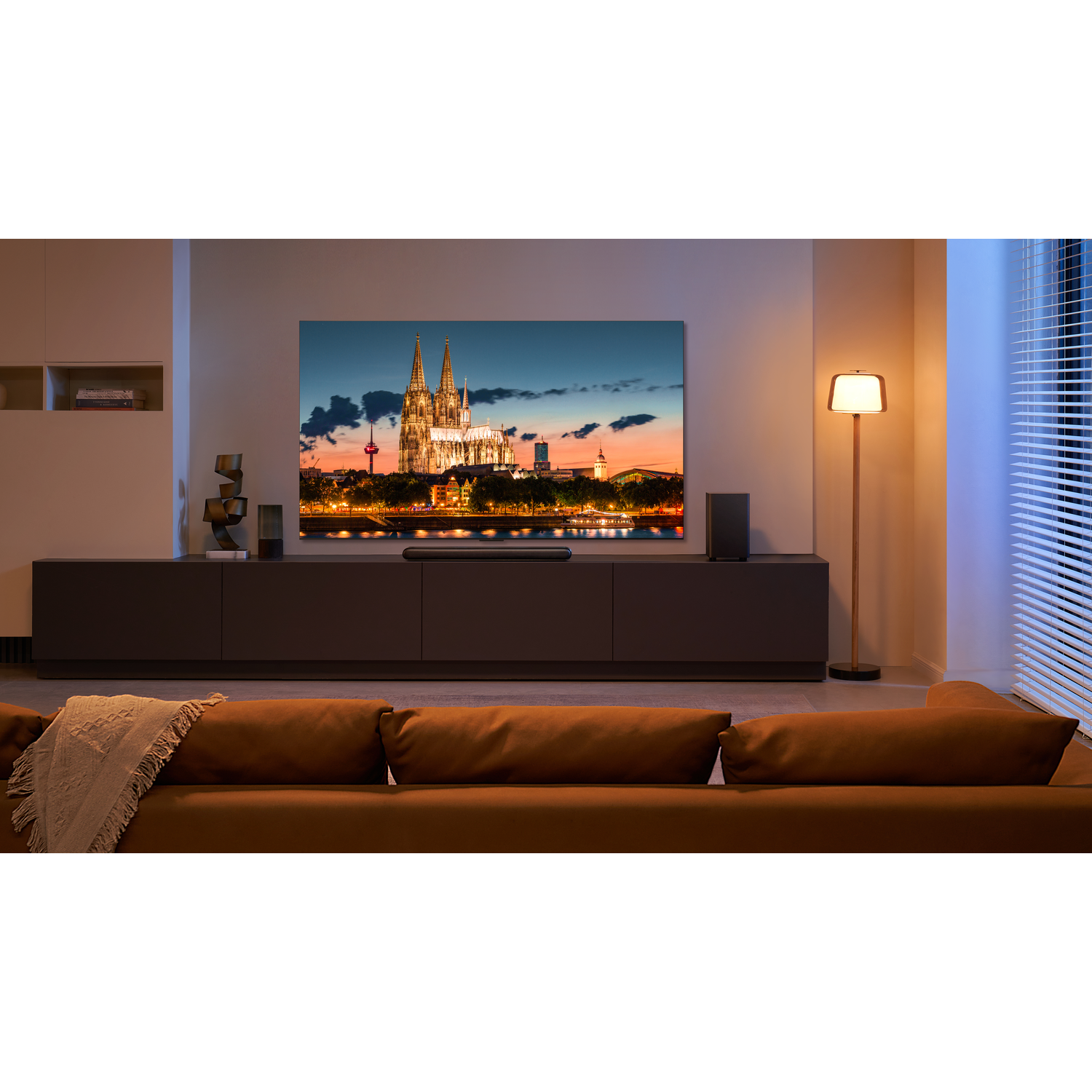 Een grote tv met een stadsgezicht, bank en lamp in de woonkamer.