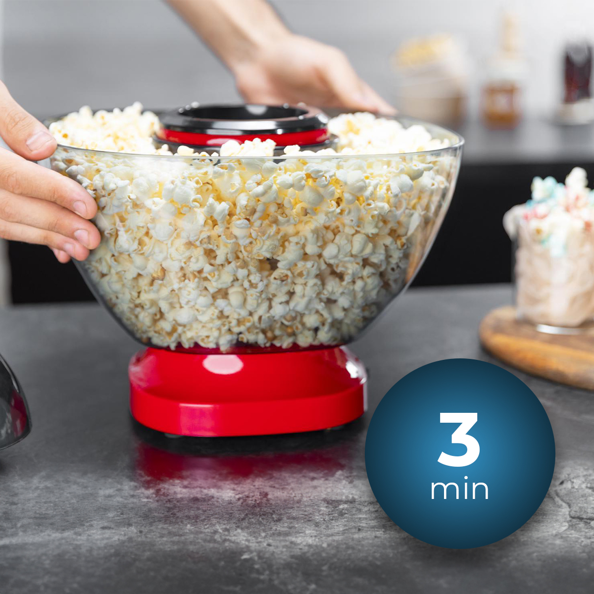 Una máquina de palomitas roja llena de palomitas, con un círculo azul que muestra '3 min'.