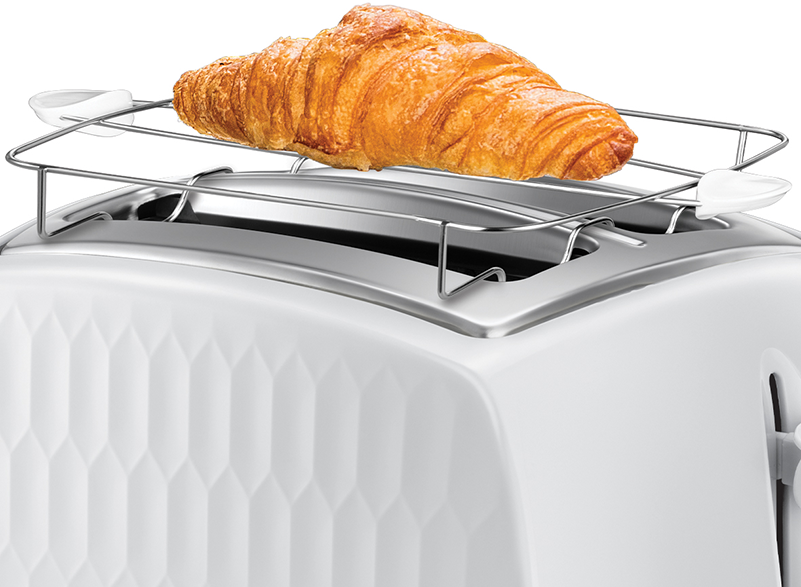 Egy fehér kenyérpirító egy croissant-val egy fémrácson. A kenyérpirítón gyémántminta van.
