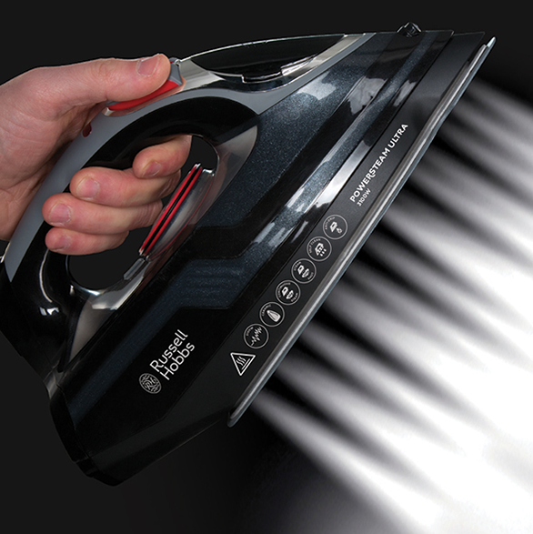 Egy fekete vasaló fehér gőzzel. A vasalót egy kéz tartja.