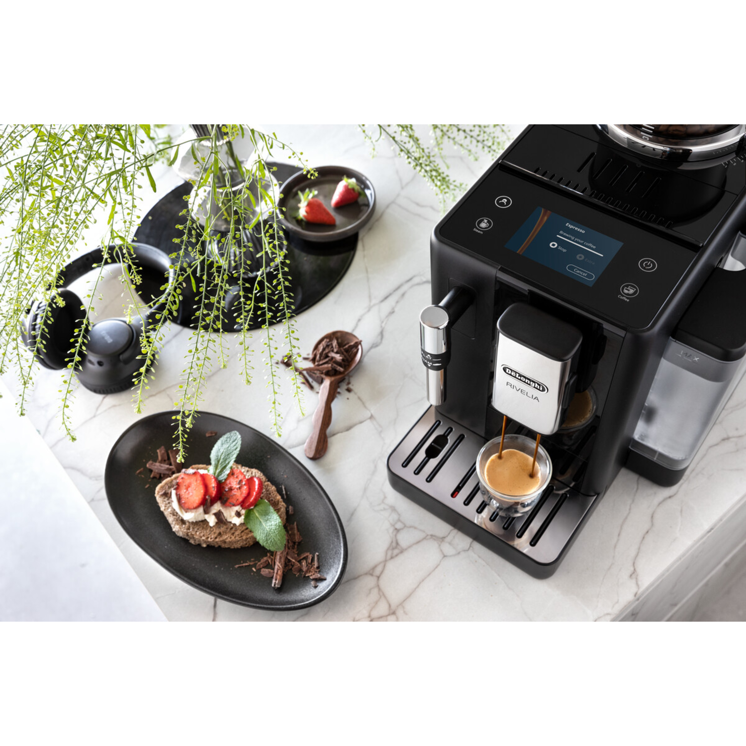 Een zwarte koffiemachine met espresso die in een glazen kopje wordt geschonken.