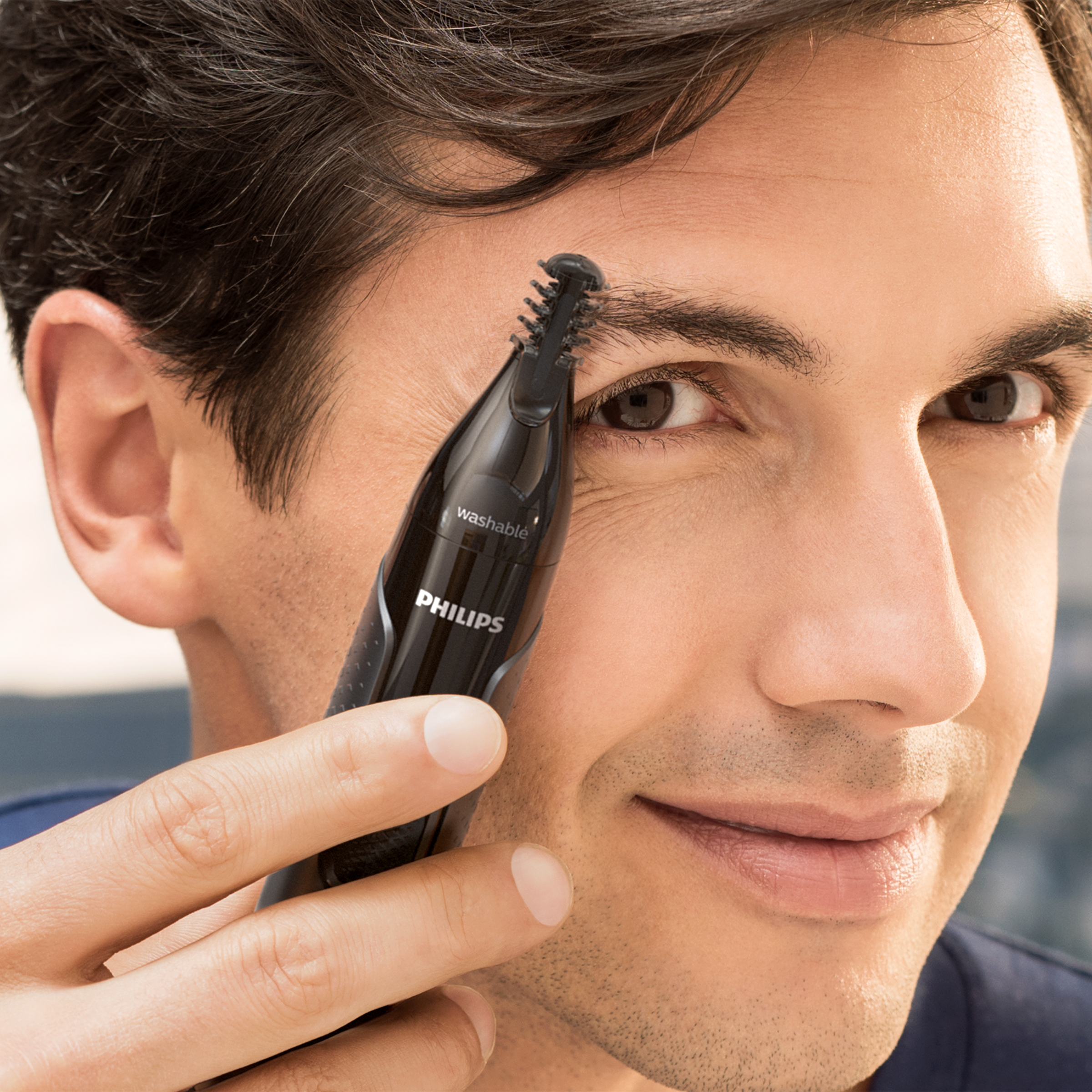 Mężczyzna przycinający brwi za pomocą urządzenia do pielęgnacji Philips.