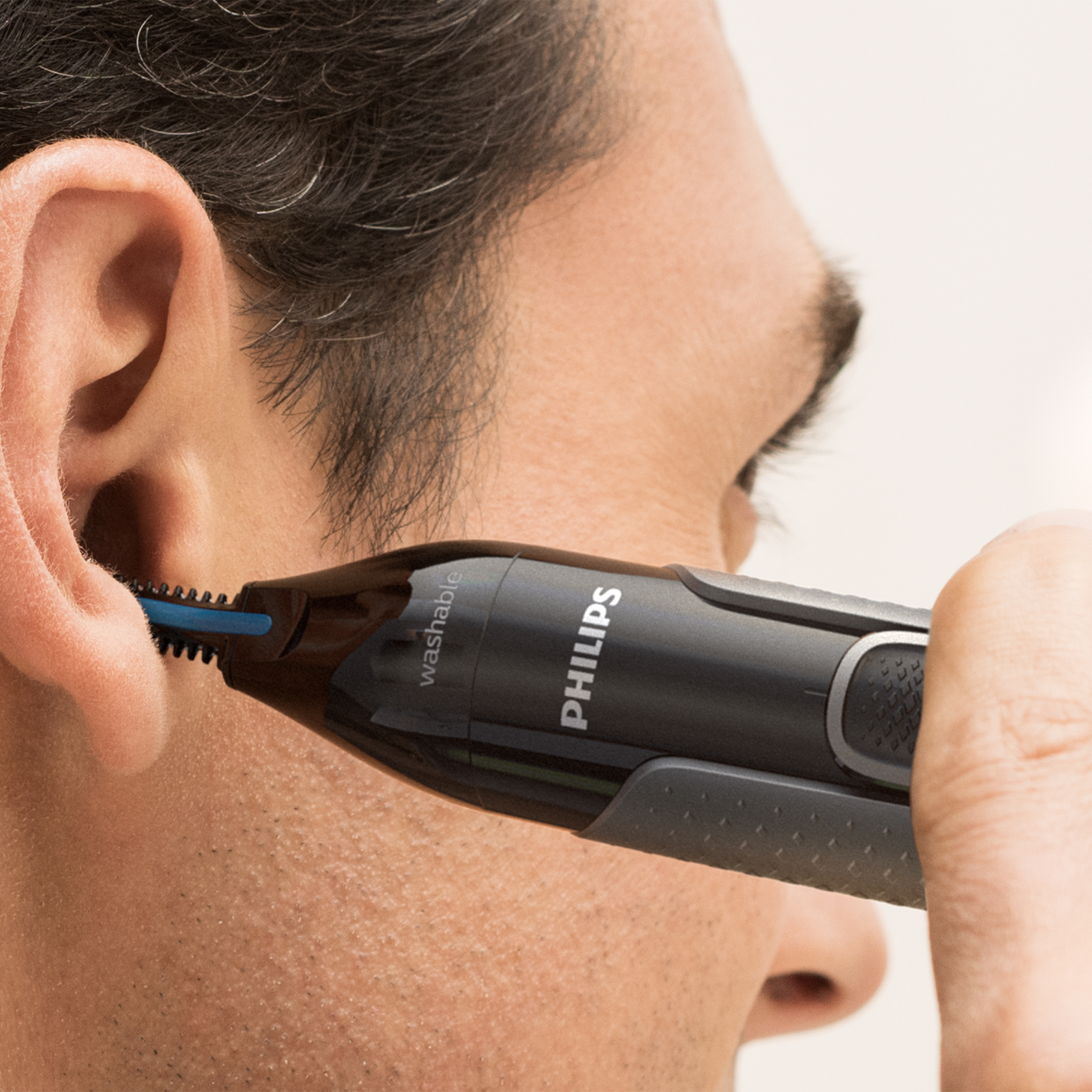 Mężczyzna przycina włosy w uszach trymerem Philips z bliska.