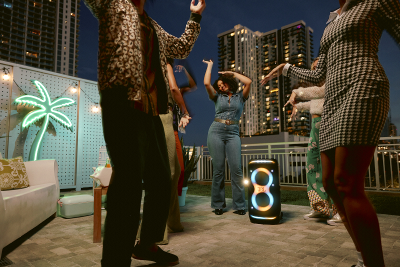 Ludzie tańczący w pobliżu głośnika JBL w nocy.