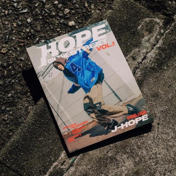 J-Hope magazin borítója. J-Hope az utcán. Kék dzseki, beton háttér.