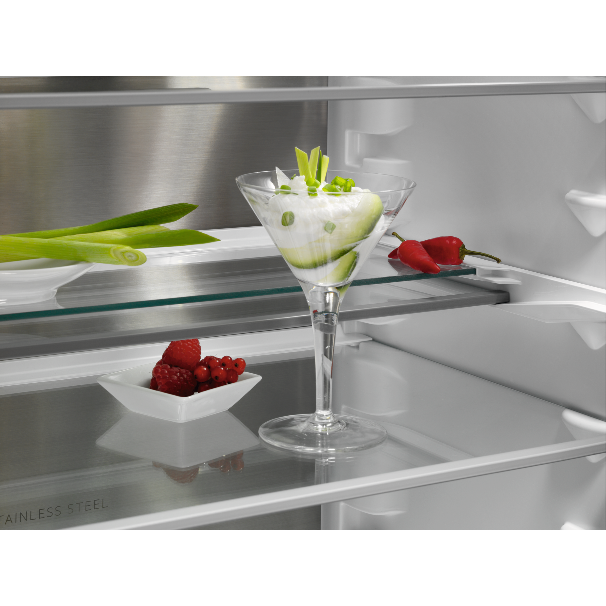 Kühlschrankinnenraum mit Glasböden. Martini-Glas mit Essen, rote Paprika.