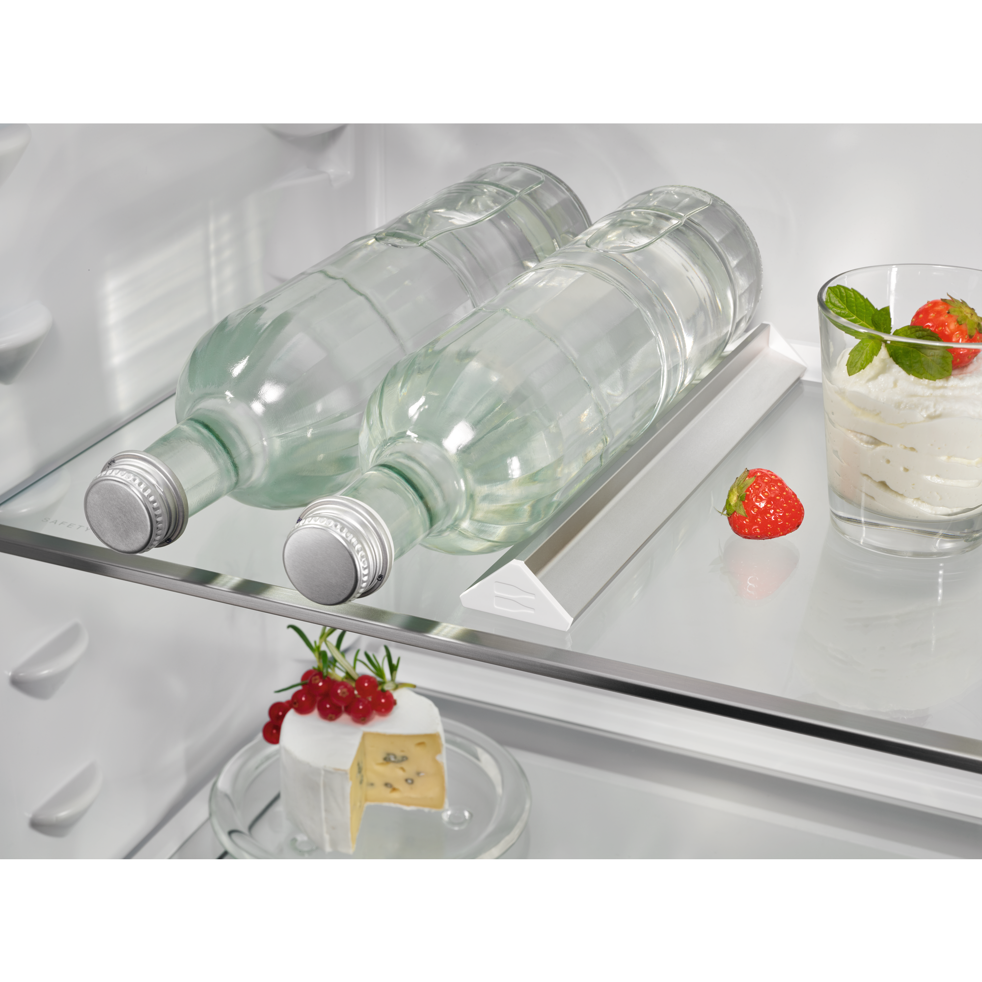 Zwei Wasserflaschen, eine Erdbeere und ein Dessert im Kühlschrank.