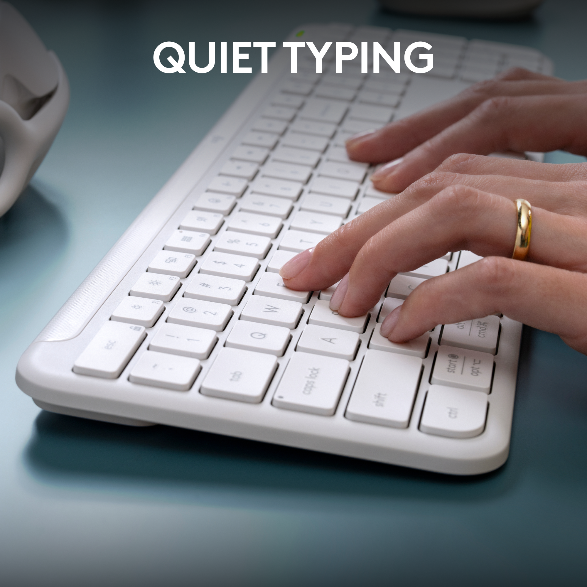 Hände, die auf einer weißen Tastatur tippen, mit den Worten 'Quiet Typing' darüber auf einer türkisfarbenen Oberfläche.