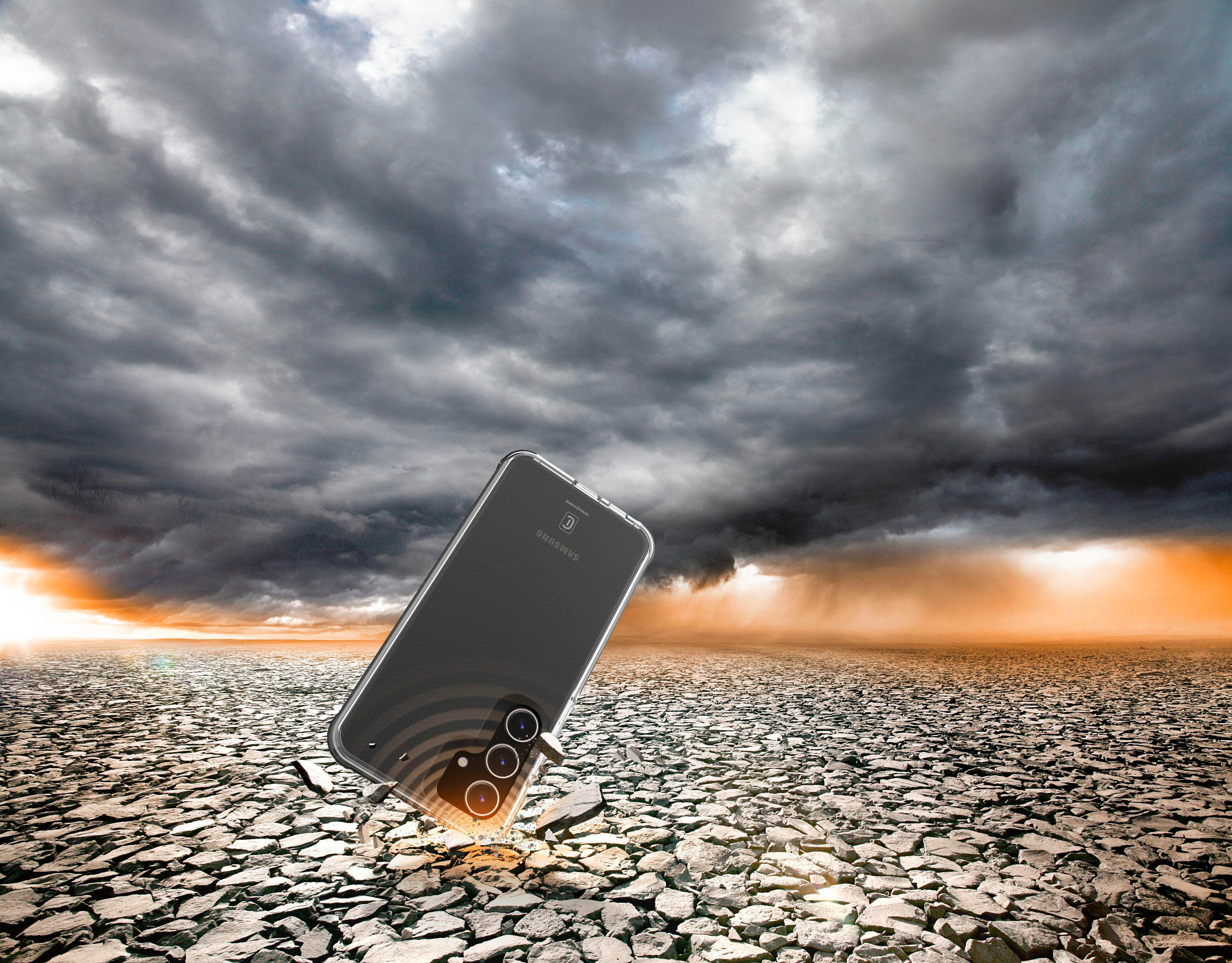 Smartphone auf rissigem Boden mit stürmischem Himmel.