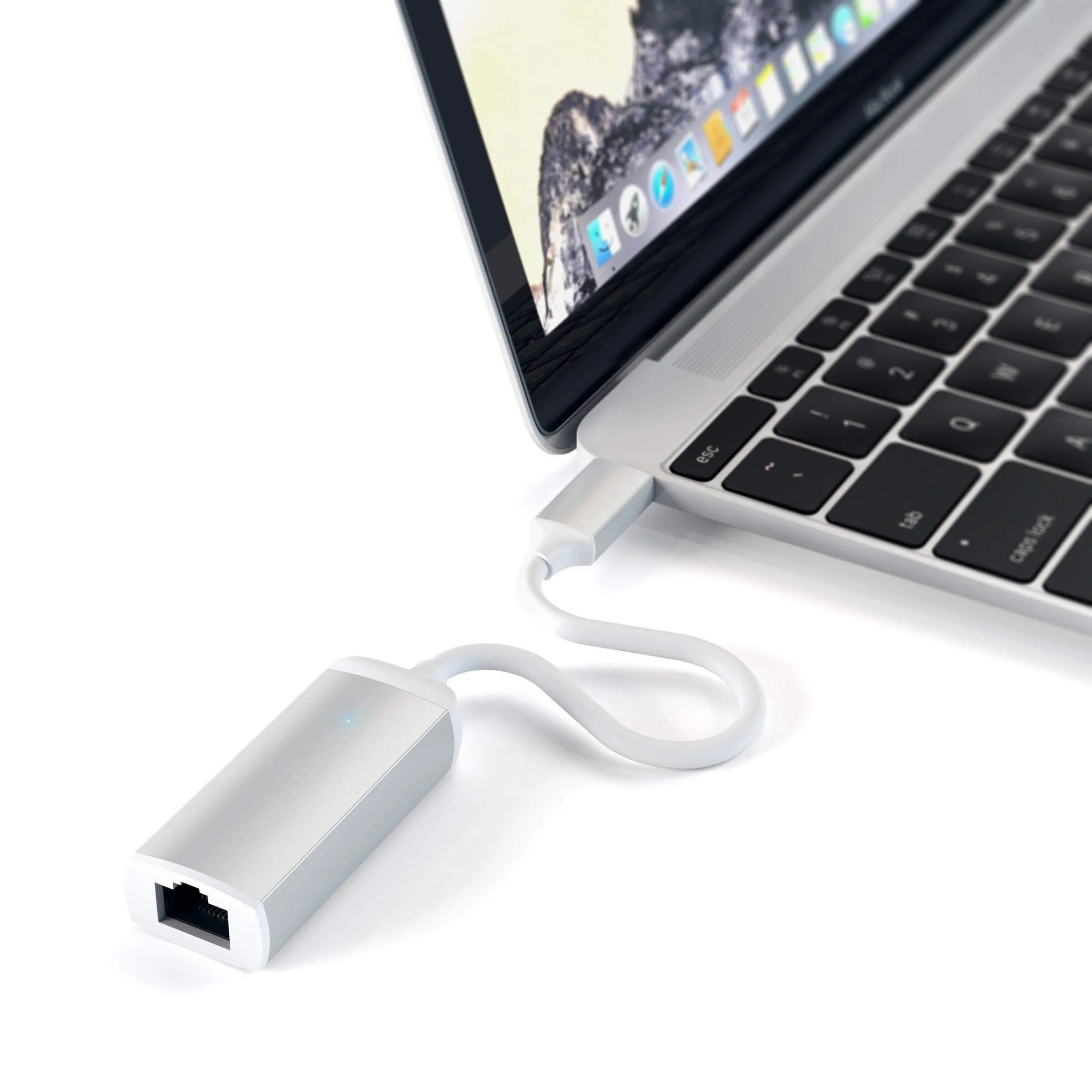 Laptop fehér kábellel és ezüst adapterrel. Fehér felület.