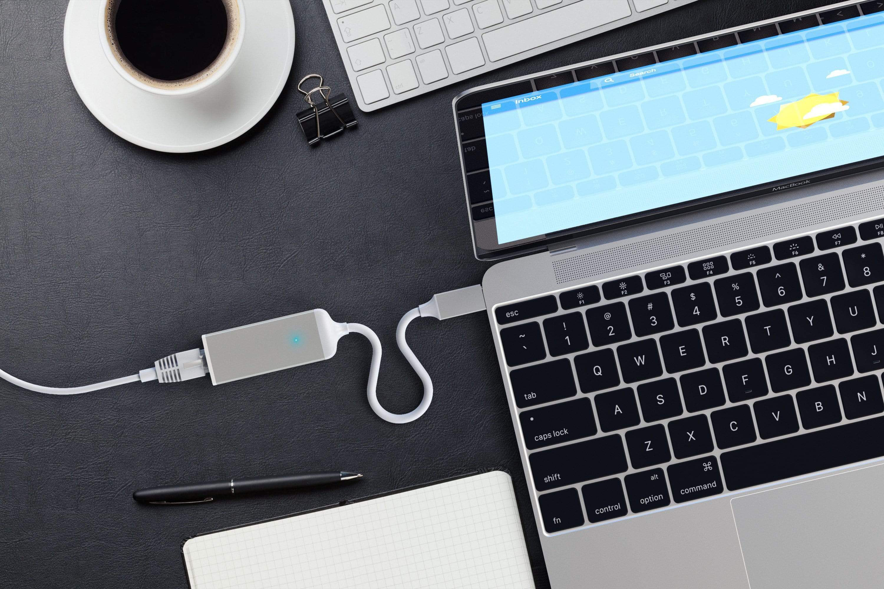 Laptop és billentyűzet, fehér USB adapterrel csatlakoztatva, valamint egy kávéscsésze.