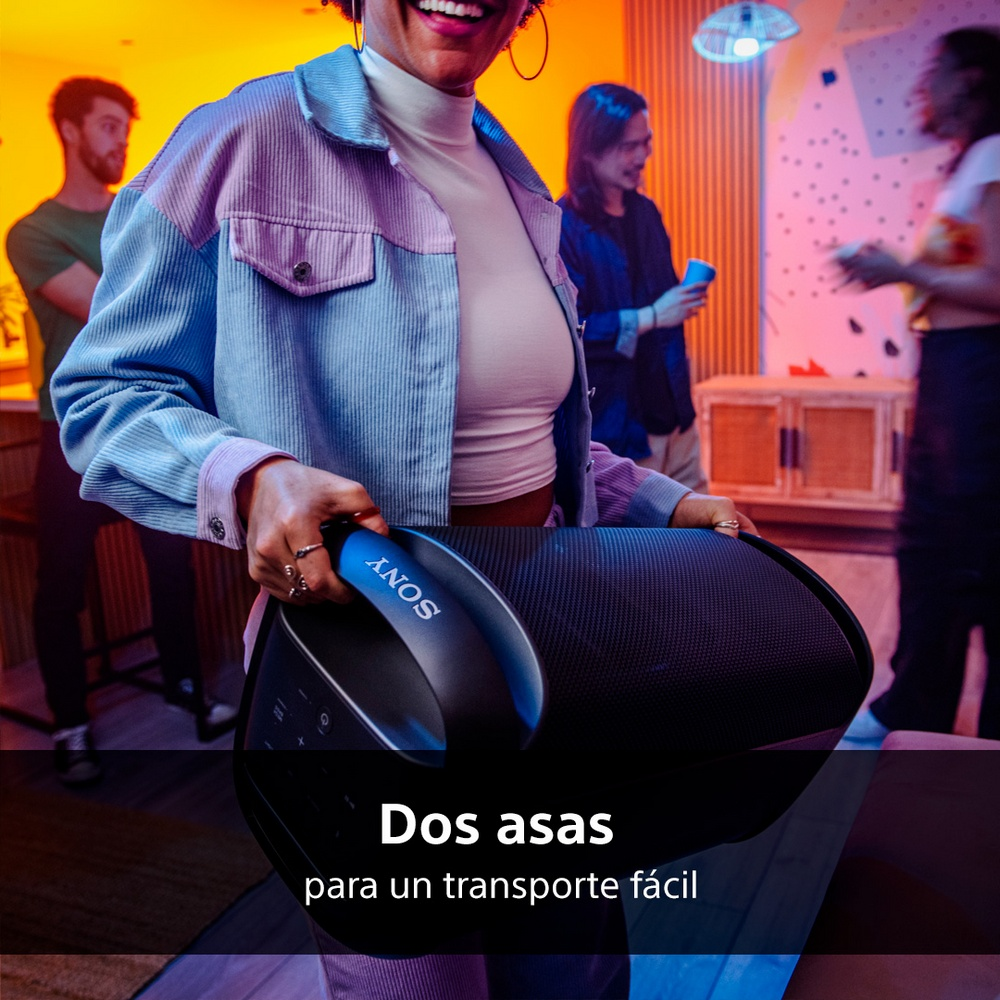 Mujer sostiene altavoz negro. Dos asas con logo Sony. Personas en el fondo.
