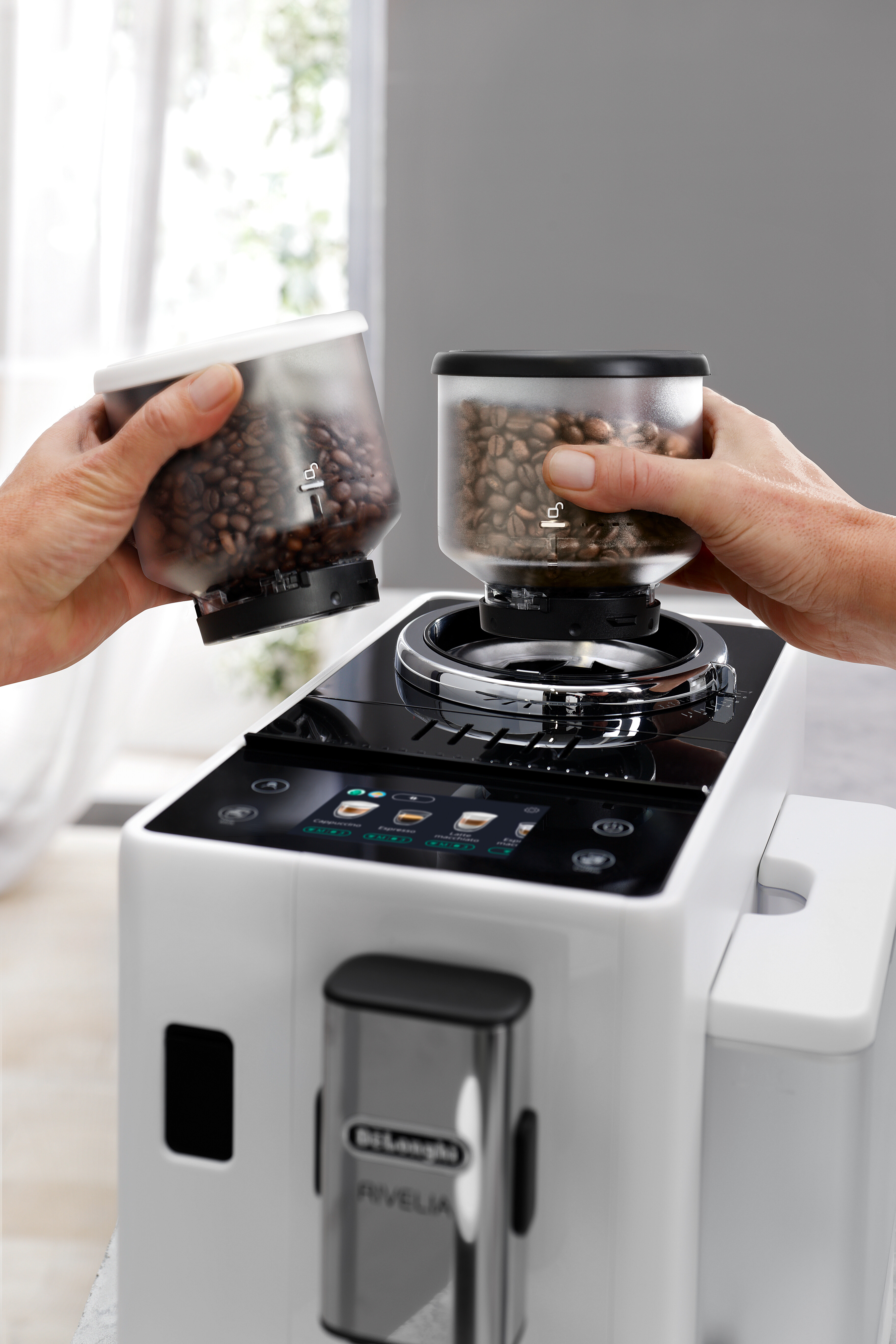 Hände halten Kaffeebohnenbehälter. Kaffeemaschine im Hintergrund.