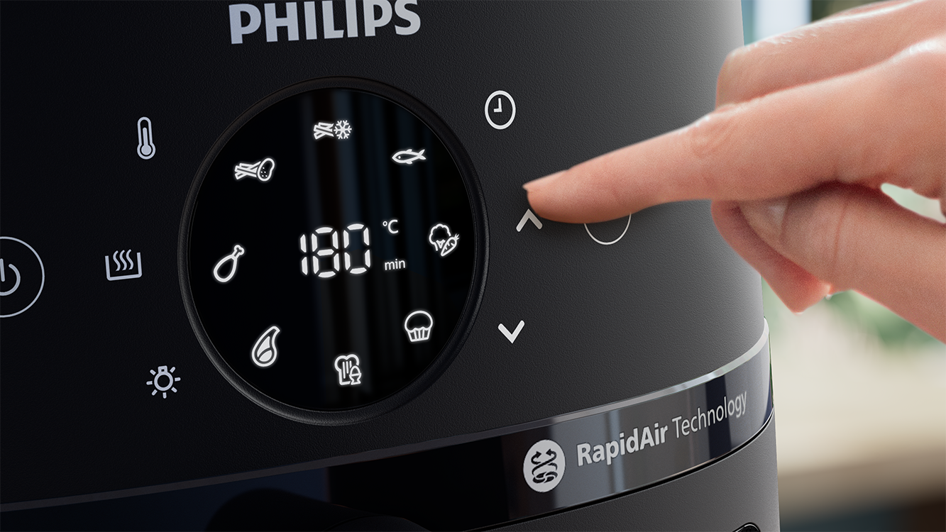 Egy Philips forrólevegős sütő vezérlőpanelje. Egy ujj érinti a felfelé mutató nyilat a sütési idő beállításához.