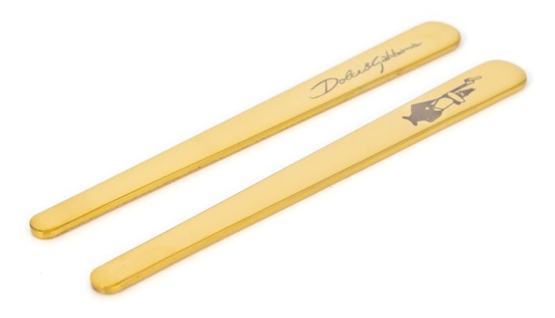 Zwei goldfarbene Kragenstäbchen mit graviertem Text und Design.