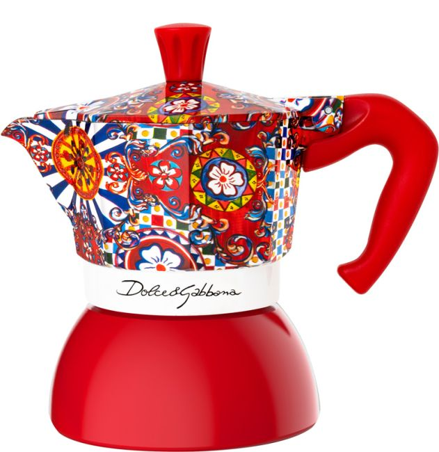 Dolce & Gabbana Kaffeemaschine. Roter Sockel, gemusterte Oberseite, roter Griff, weißes Band mit Logo.