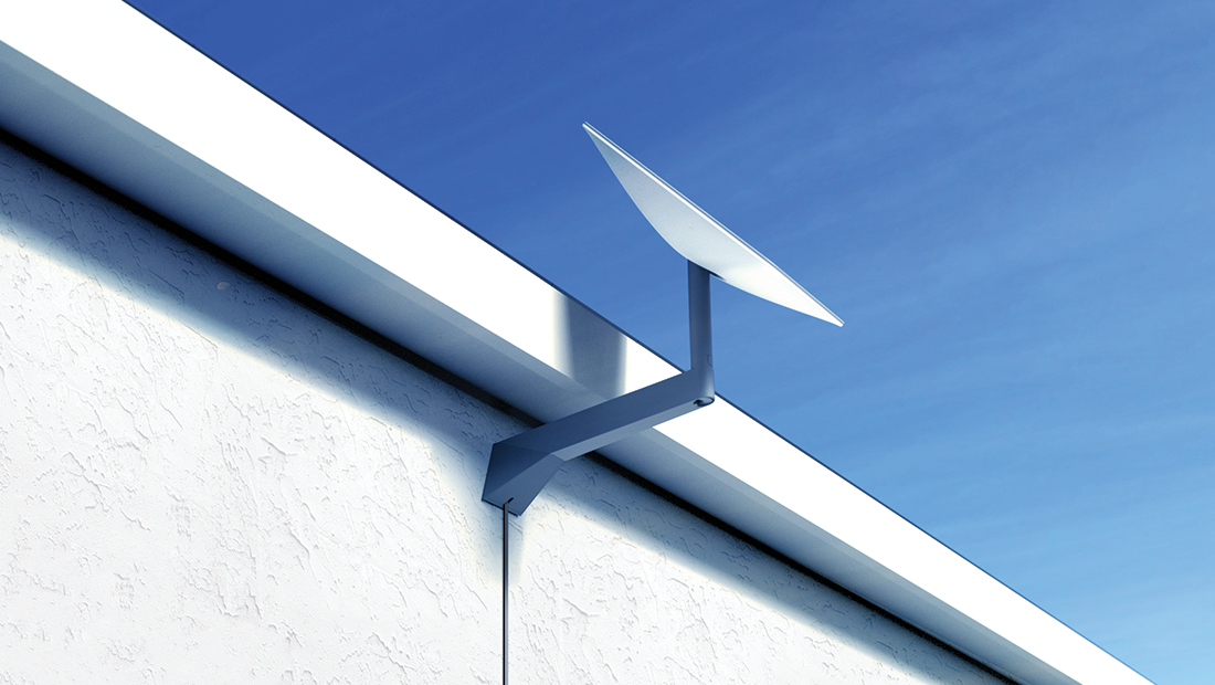 Satellitenschüssel an weißer strukturierter Wand vor blauem Himmel.