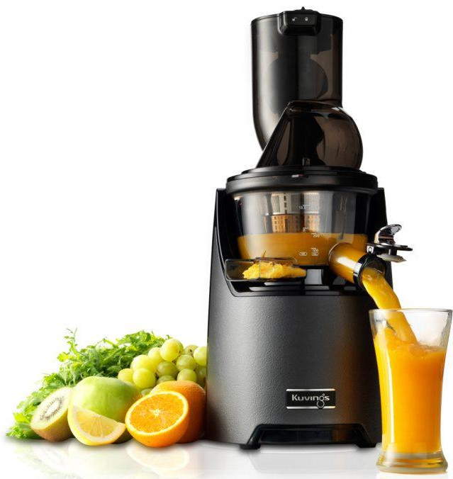 Czarna wyciskarka z sokiem pomarańczowym wlewanym do szklanki, otoczona owocami.