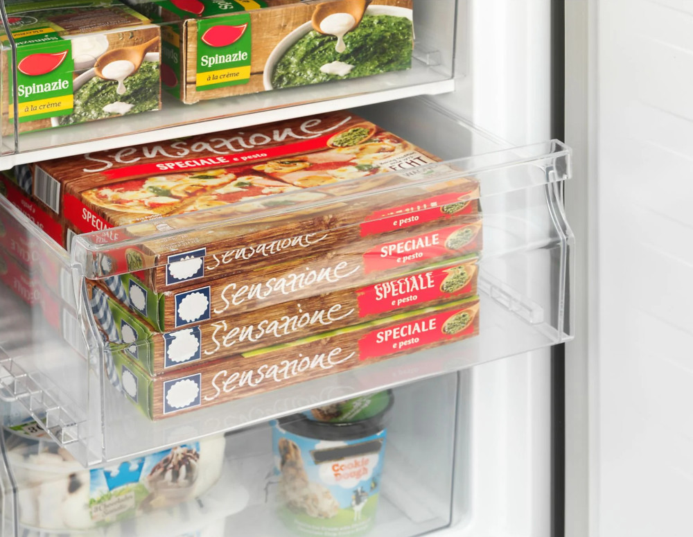 Étagère de réfrigérateur avec pizzas surgelées et épinards. Étagère en plastique transparent.