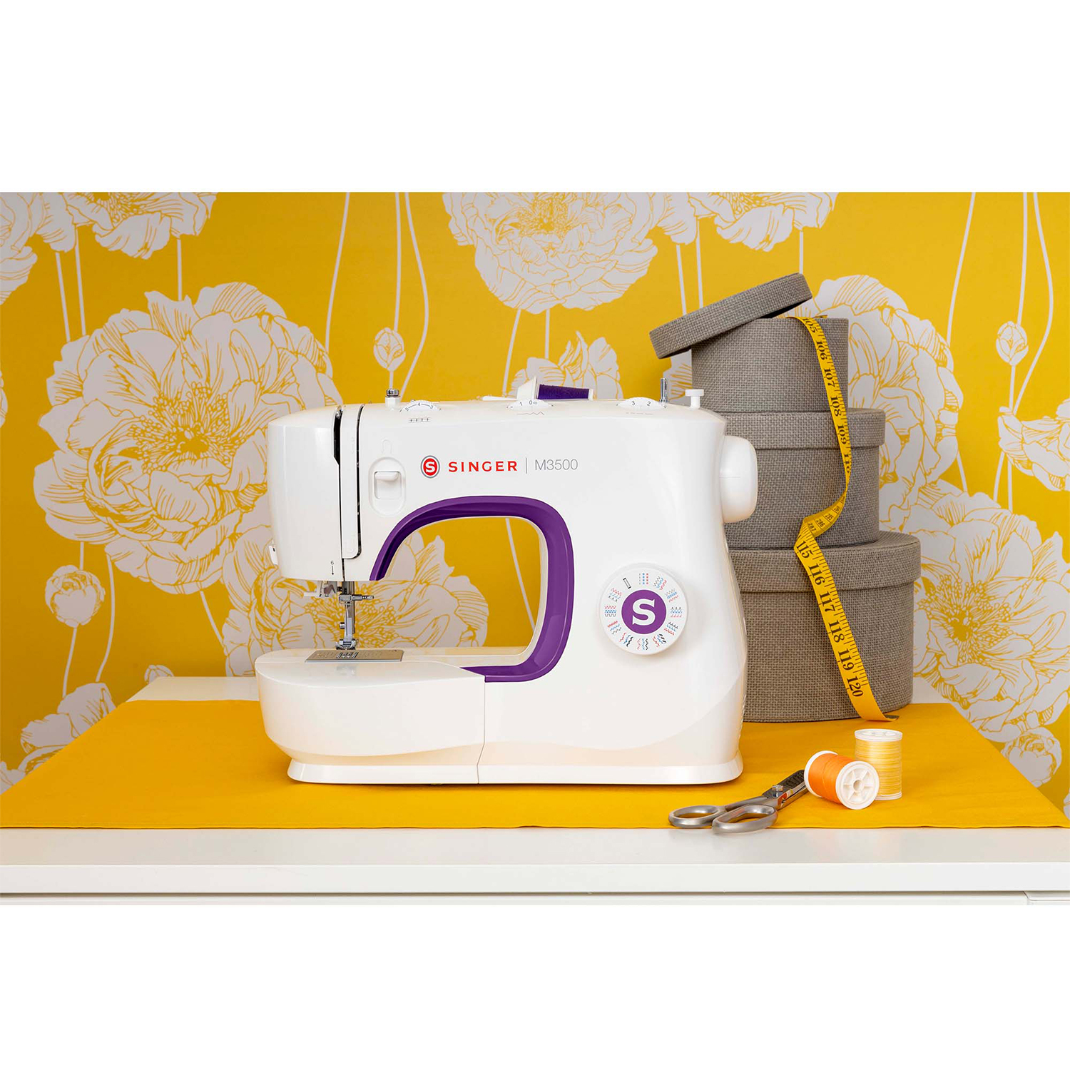 Macchina da cucire bianca con dettagli viola. Sfondo giallo con motivo floreale. Forbici e metro a nastro.