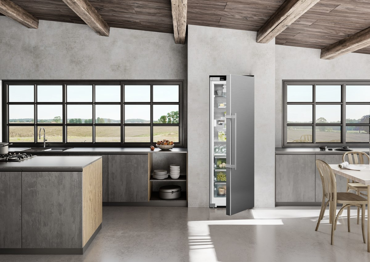 Moderne Küche mit großem Kühlschrank und Fenstern. Betonarbeitsplatten, Holzbalken und Boden.