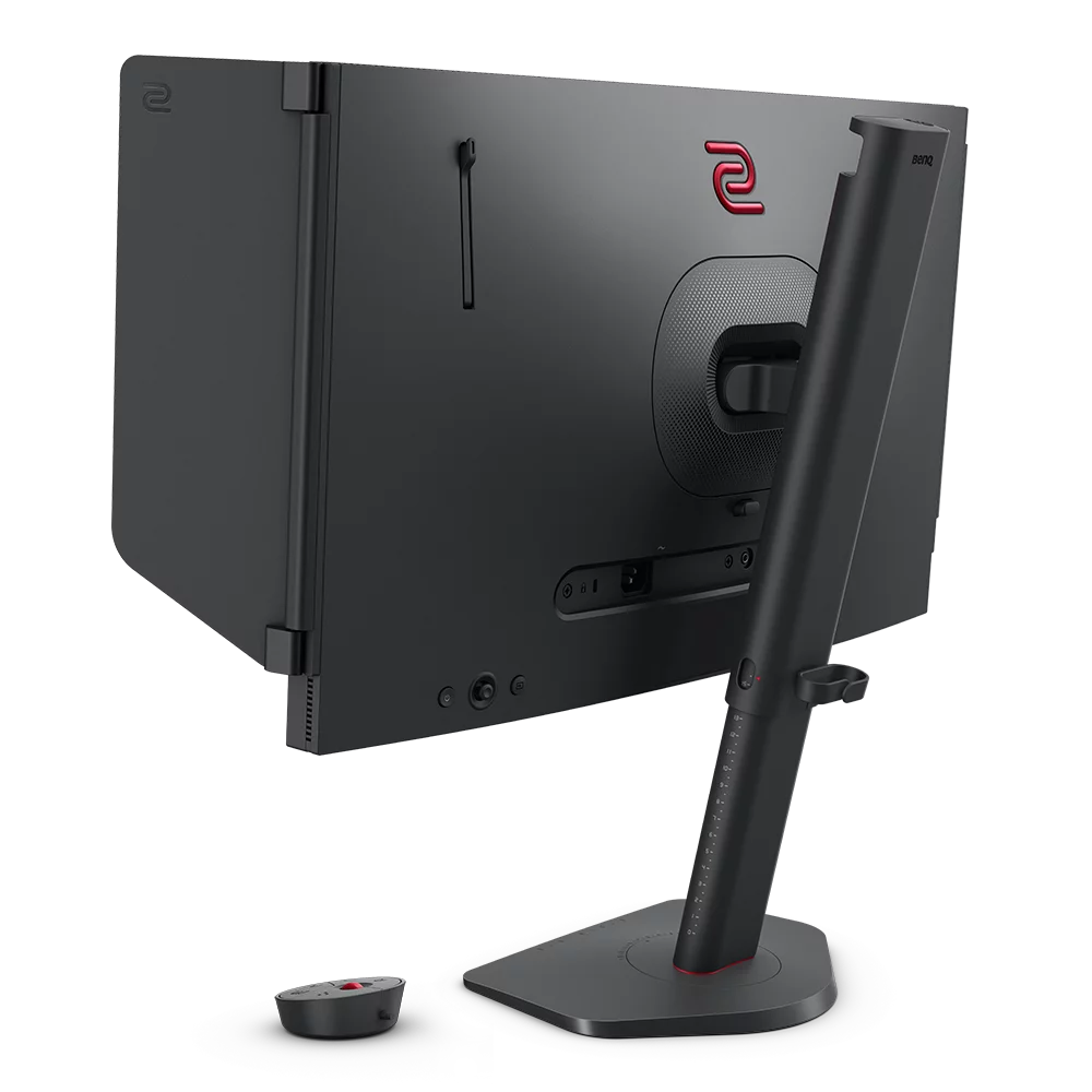 Vista trasera de monitor negro con logo rojo y soporte. Mando a distancia abajo.