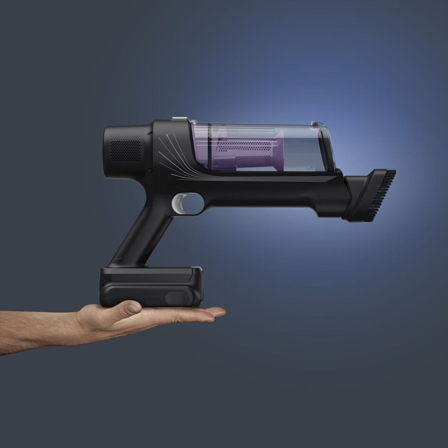 A black vacuum cleaner held in a hand. It has a transparent purple dustbin section and a black battery.