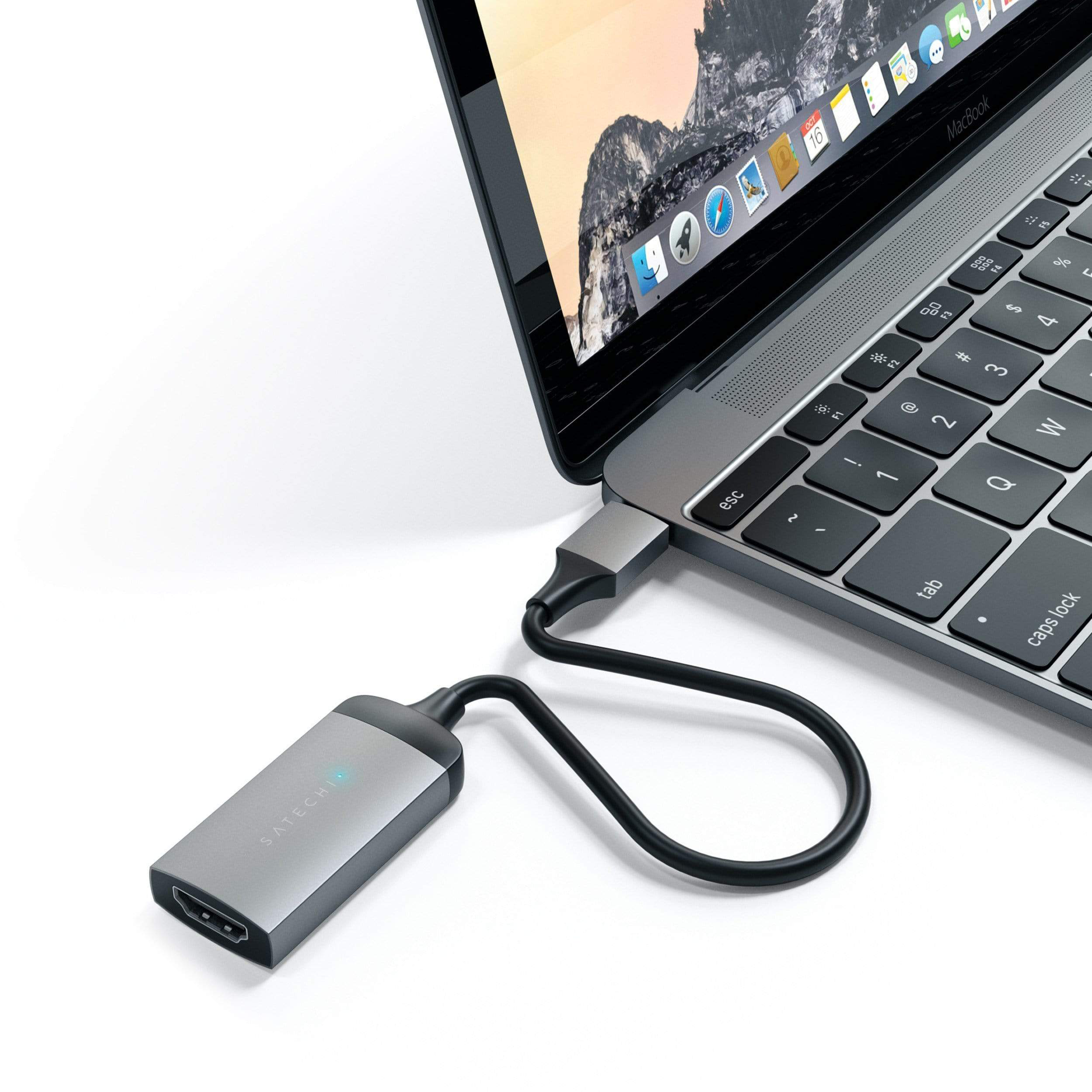Egy laptop egy ezüst adapterhez csatlakozik fekete kábelen keresztül.