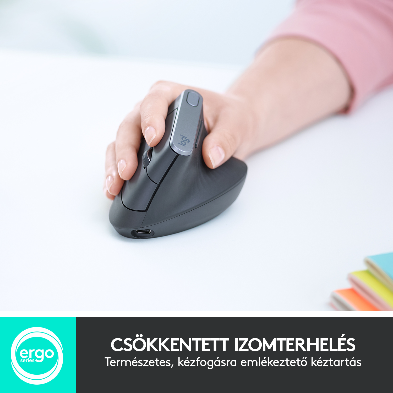 Egy személy keze egy fekete ergonomikus egéren. Fehér felület alatta szöveggel.