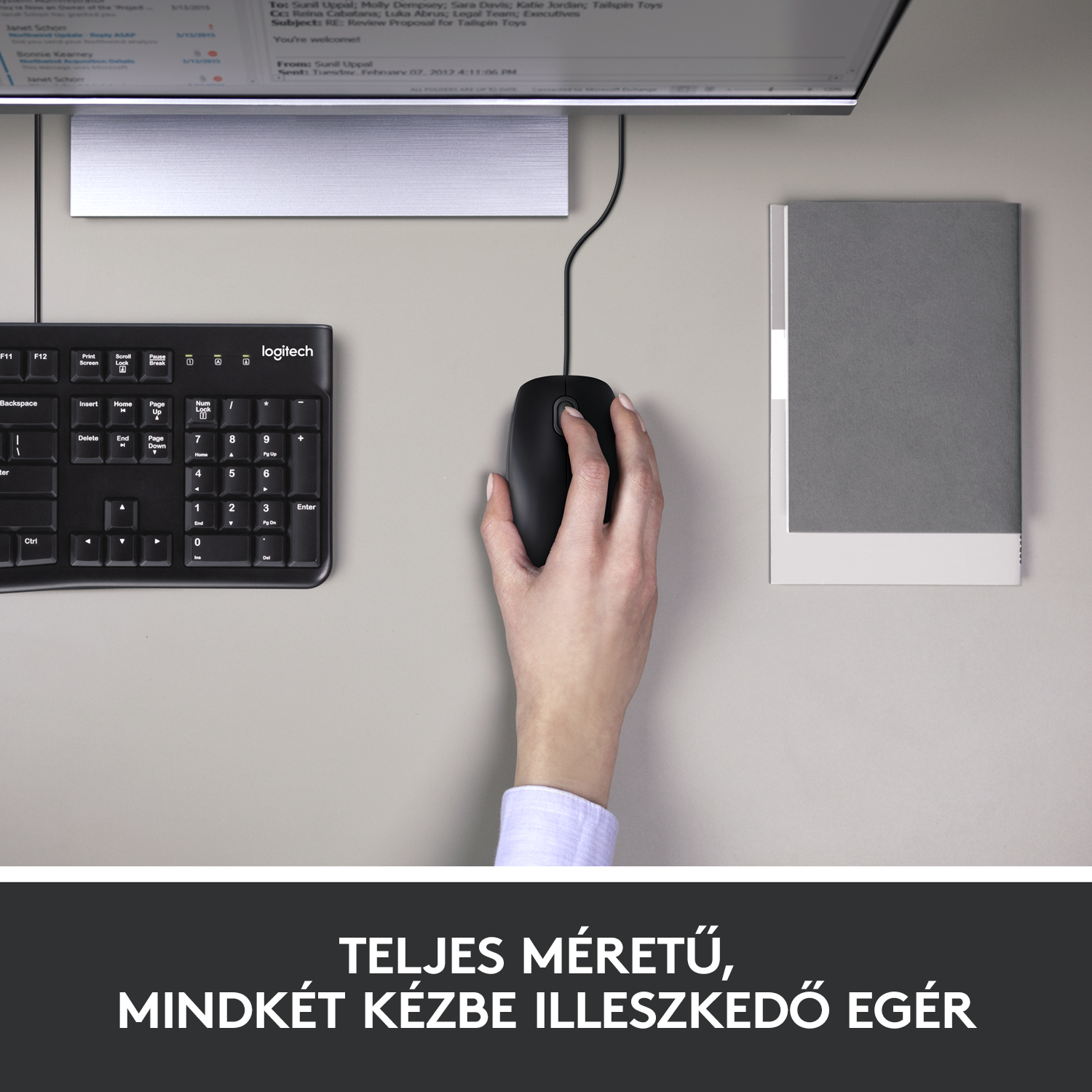 Kéz fekete Logitech egeret használ az asztalon billentyűzettel és könyvvel. Fehér.