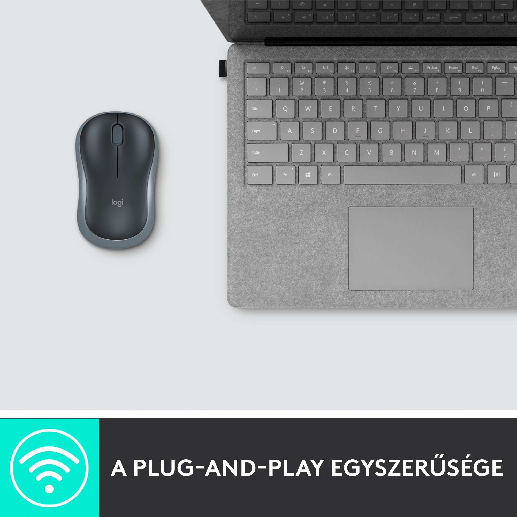 Szürke egér egy laptop billentyűzete mellett. Az egér fehér felületen van, alatta wifi szimbólummal.