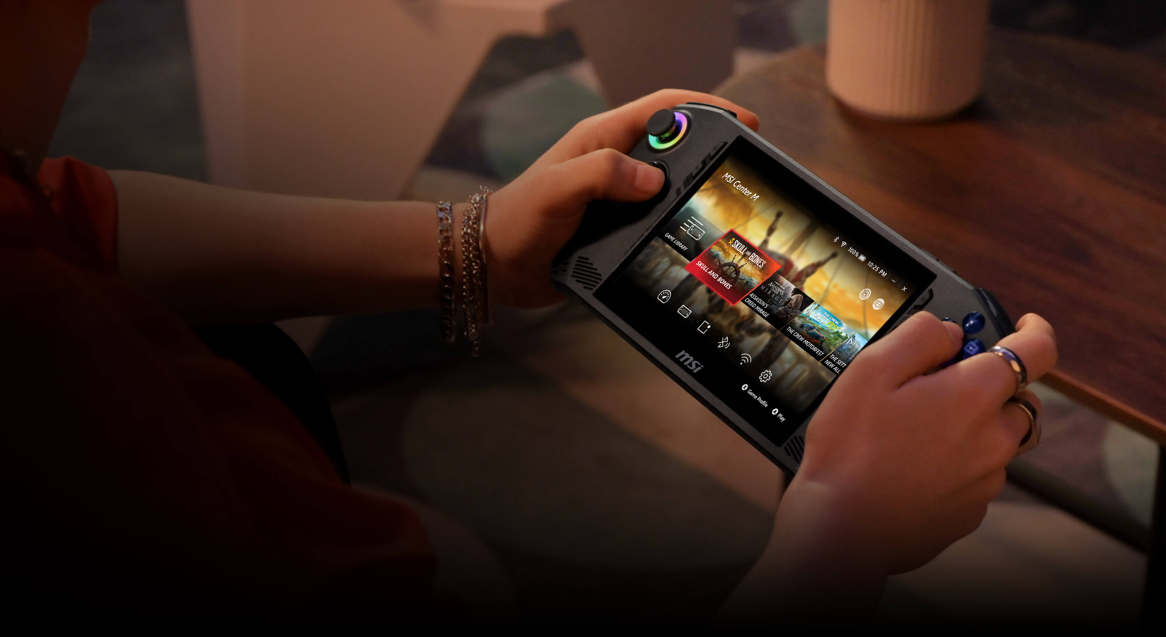Personne tenant une console de jeu portable. L'écran affiche l'interface du jeu. Mains et bracelet visibles.