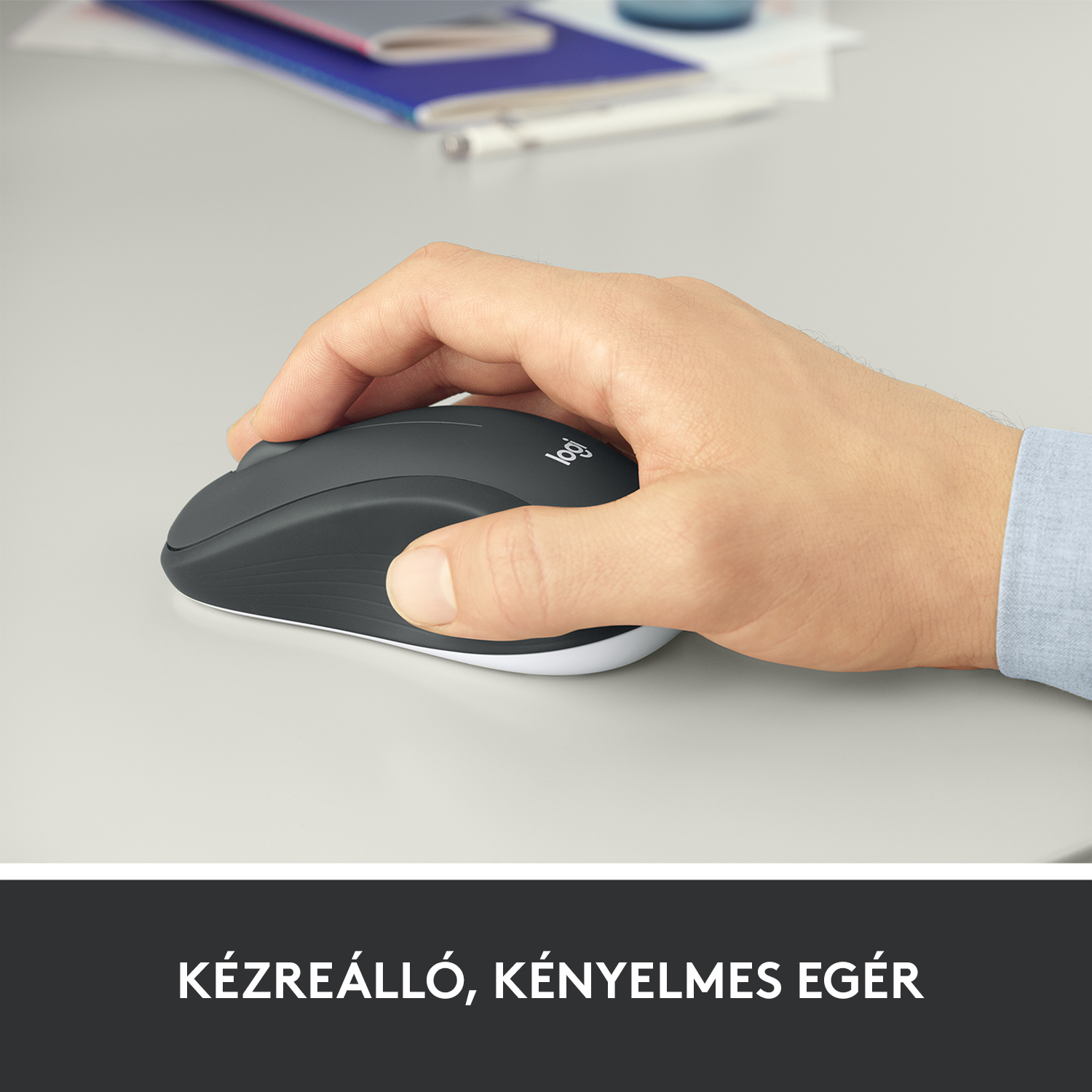 Egy kéz egy sötétszürke Logitech egeret használ egy világosszürke felületen.