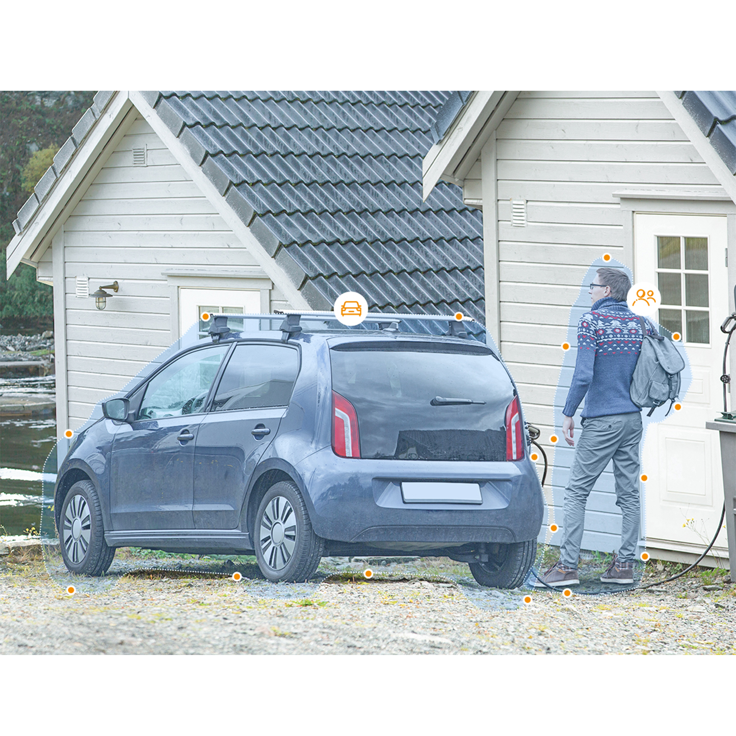 Un'auto in carica, con una persona vicino, una casa sullo sfondo.