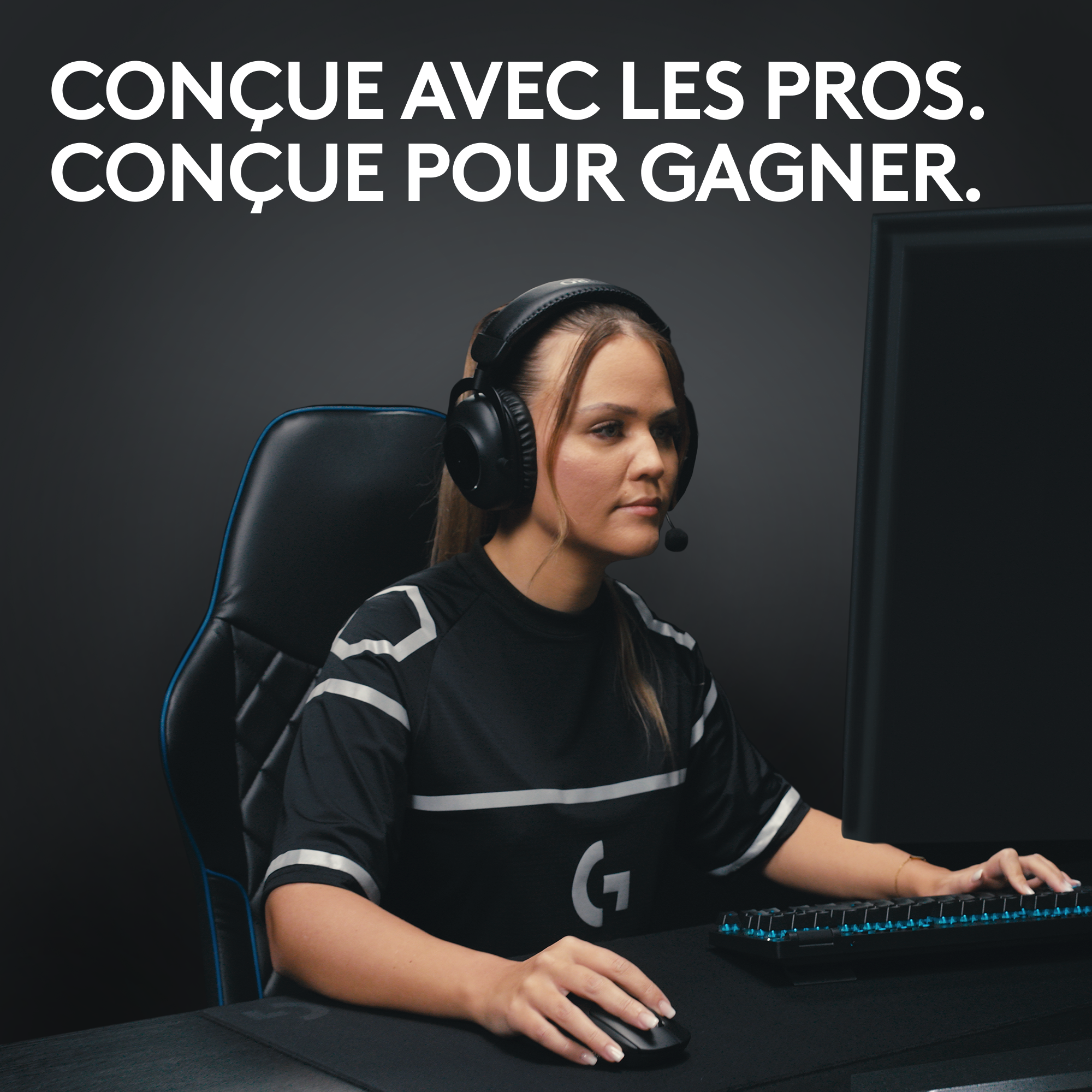 Une femme portant un casque utilisant une souris et un clavier, jouant à un jeu, avec un logo G sur son t-shirt.