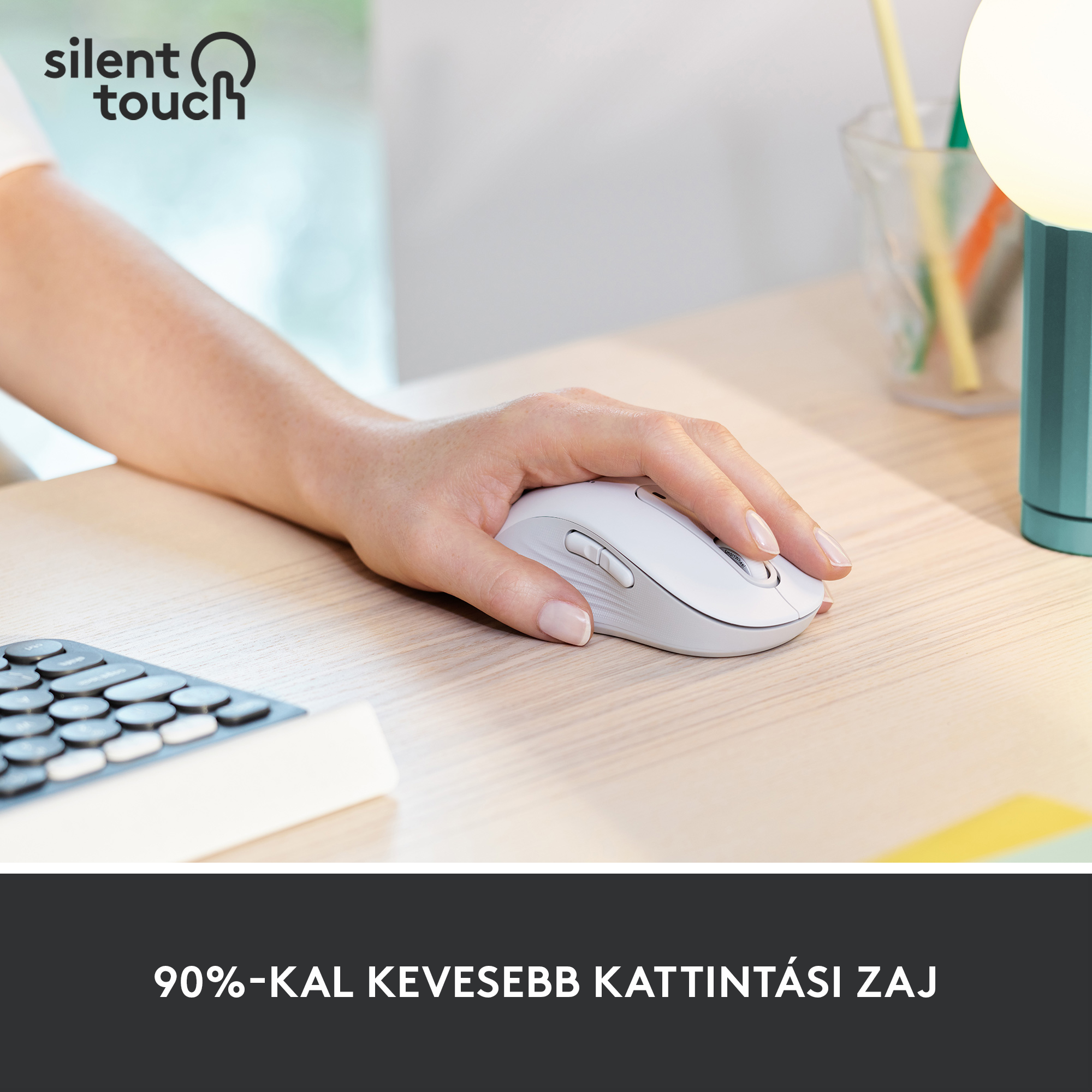Kéz fehér egeret használ faasztalon. Egér a billentyűzet és a lámpa közelében.