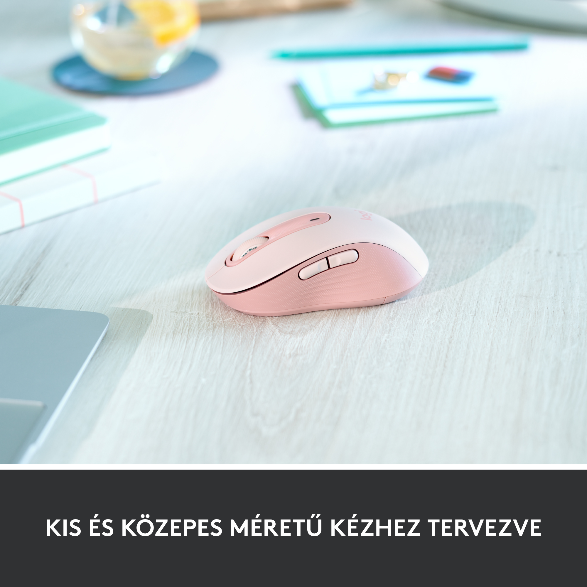 Egy rózsaszín számítógépes egér egy fa asztalon, a szöveggel: 'kis és közepes méretű kézhez tervezve'.