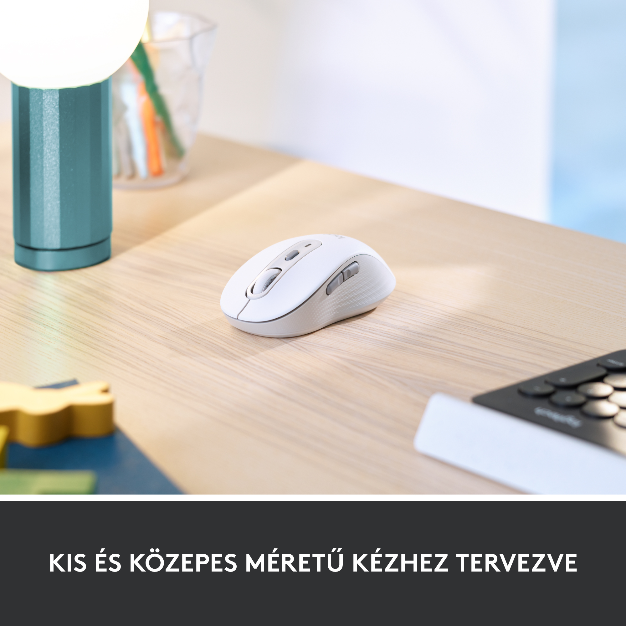 Fehér egér fa asztalon, lámpa és billentyűzet mellett.