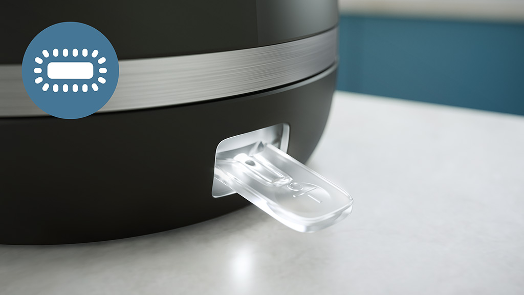 Zbliżenie czarnego urządzenia z przezroczystym plastikowym języczkiem wystającym z boku. Ikona niebieskiego koła.