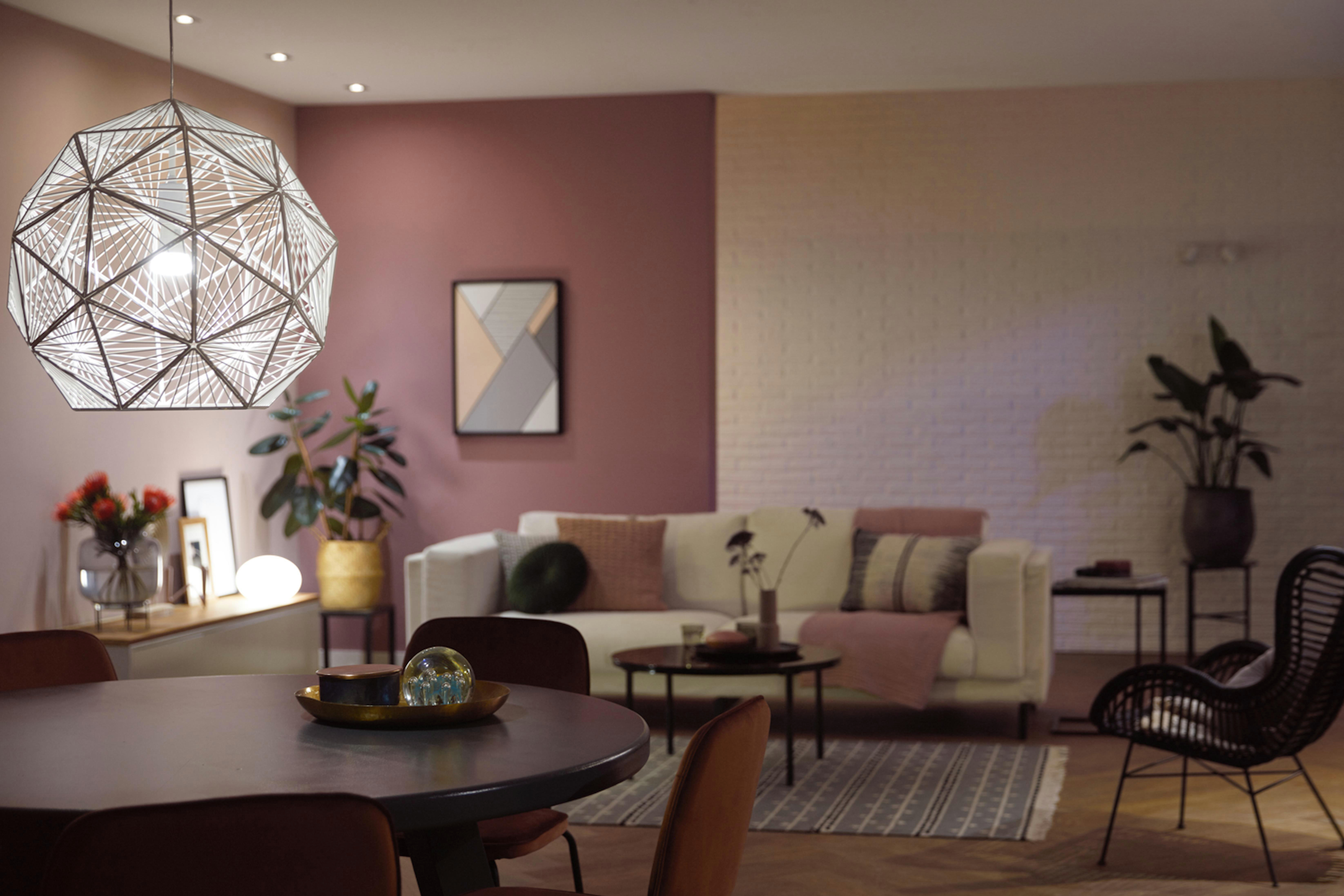 Ein modernes Wohnzimmer mit Pendelleuchte, Couch und farbenfrohen Wandkunstwerken.