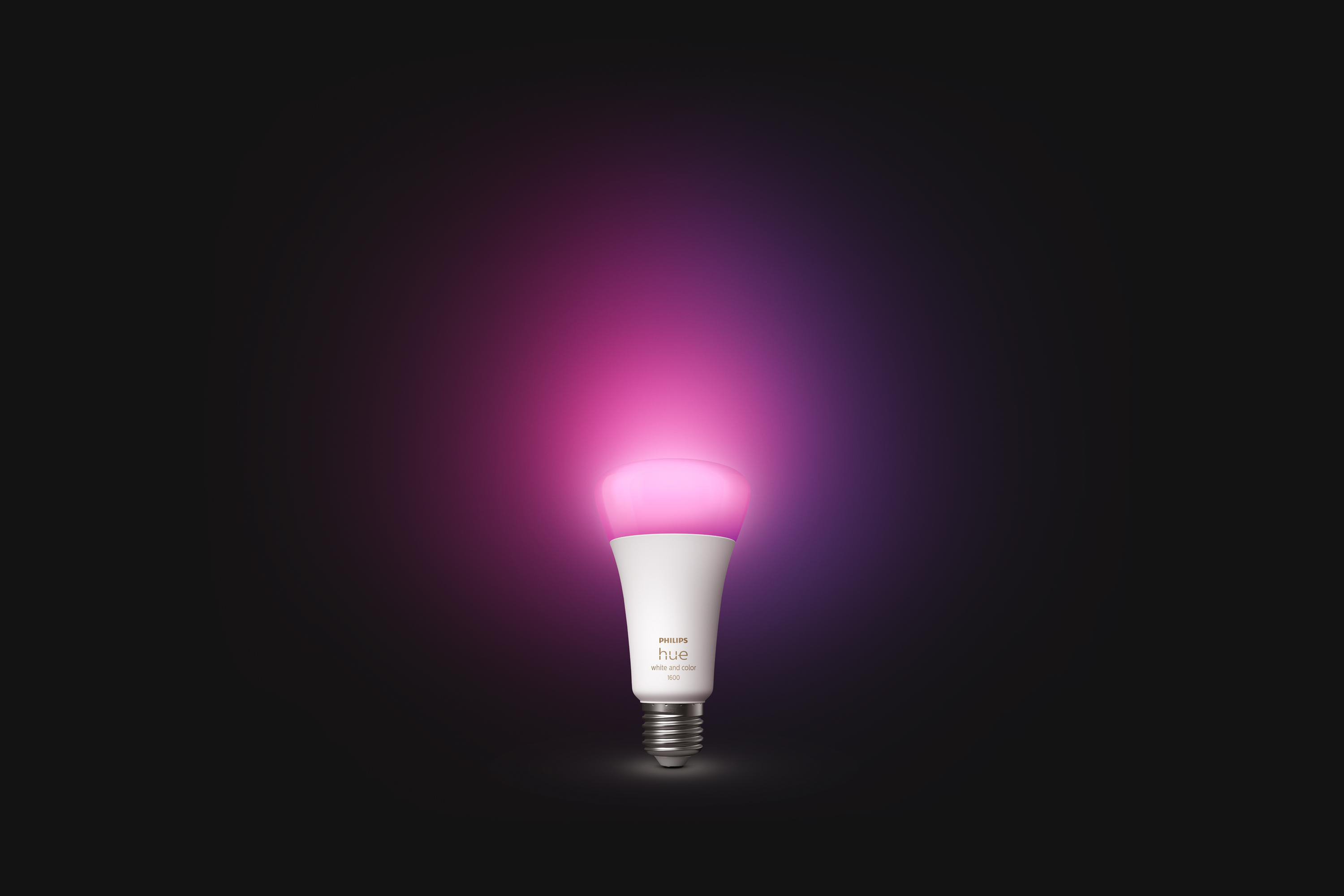 Eine weiße Smart-Glühbirne strahlt pinkes Licht vor schwarzem Hintergrund aus. Sie hat einen weißen Sockel.