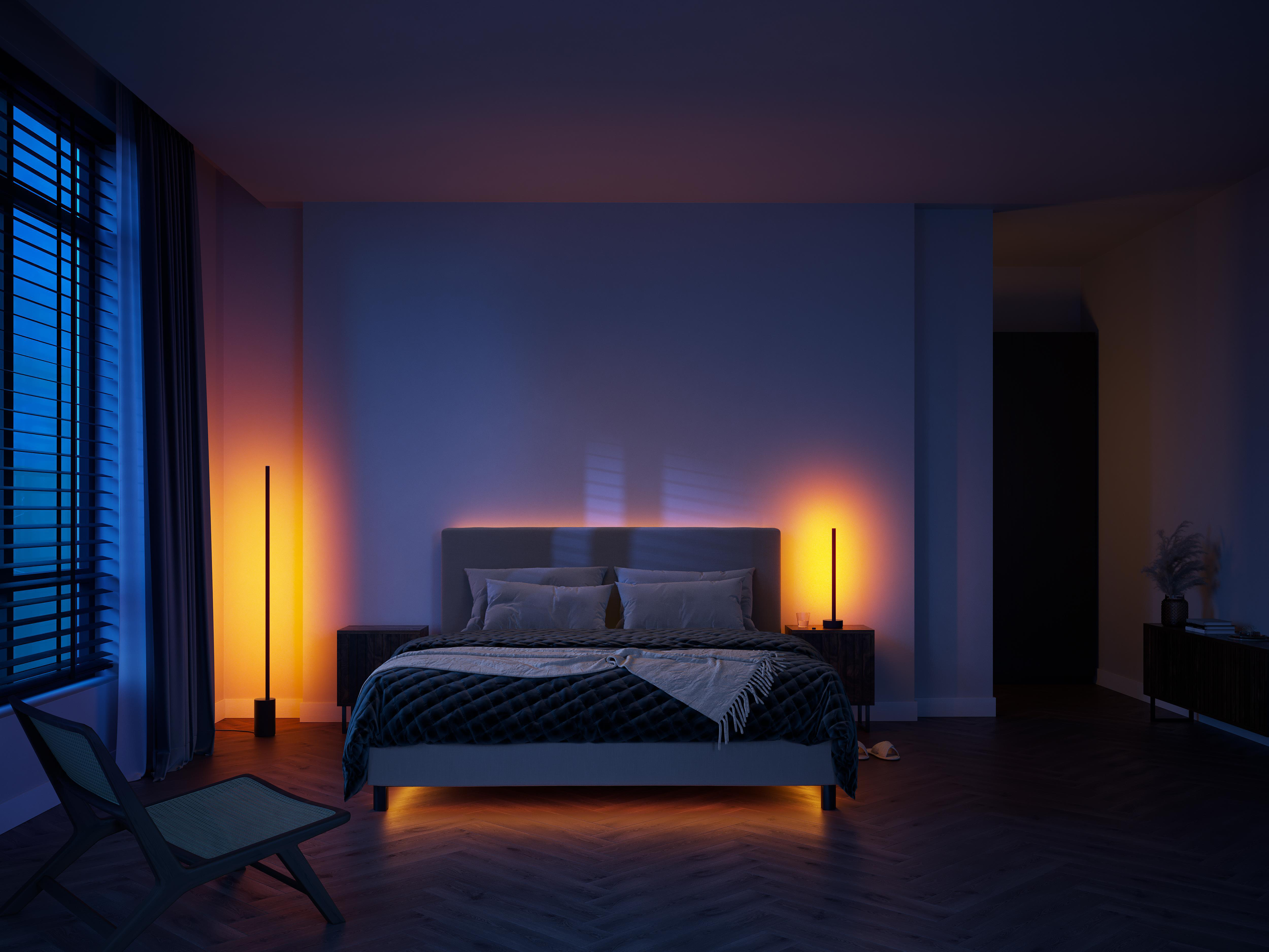 Schlafzimmer bei Nacht mit zwei vertikalen Lampen. Bett mit Lichtern und Fenster mit Jalousien, sowie ein Stuhl.
