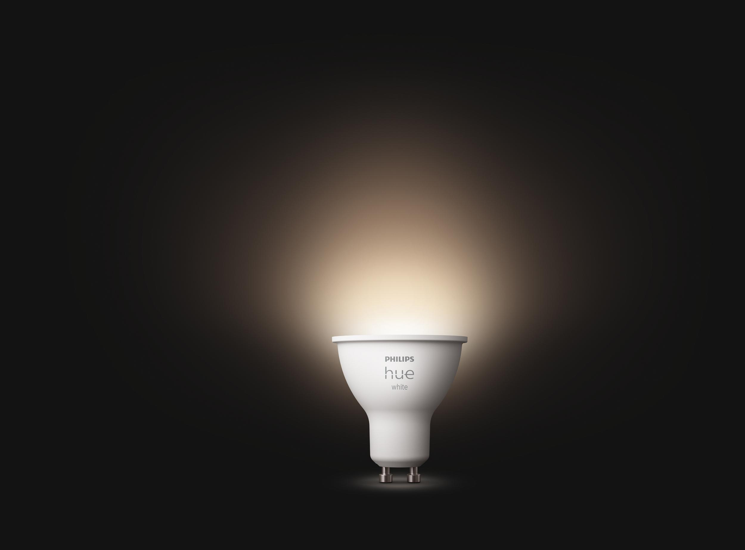 Eine weiße Philips Hue-Glühbirne leuchtet vor dunklem Hintergrund und strahlt Licht aus.