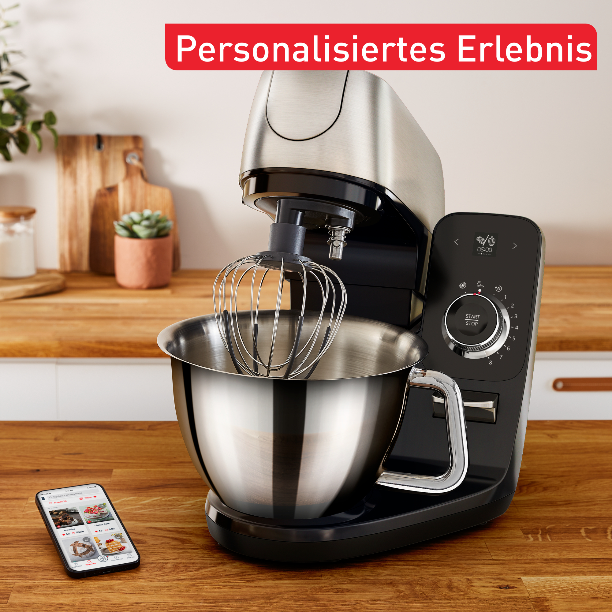 Küchenmixer mit Schüssel und Schneebesen. Telefon mit Rezepten liegt auf der Theke.
